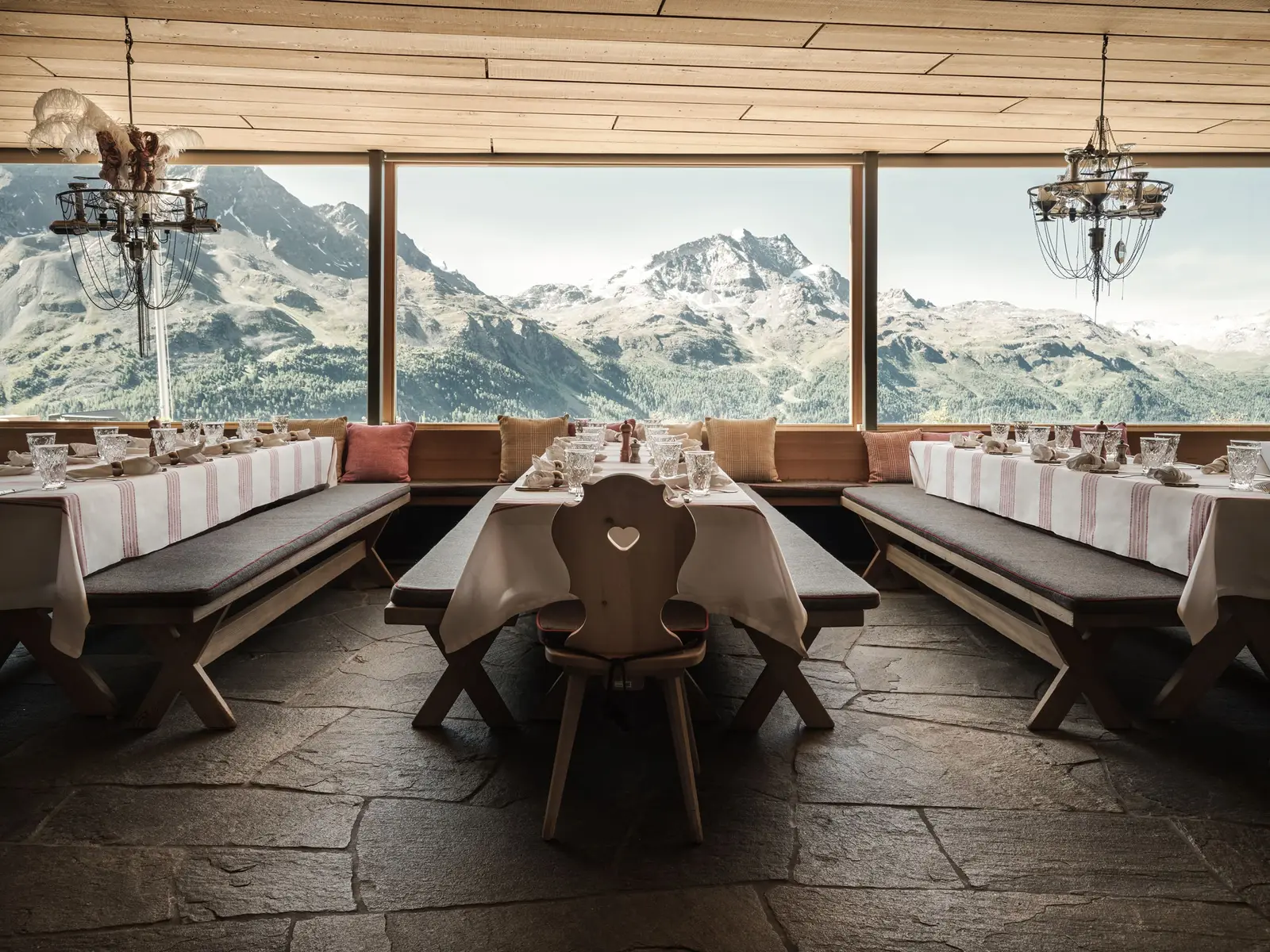 The dining room at Paradiso: tables laid with striped cloths, cushioned benches and picture windows onto the Engadin peaks.