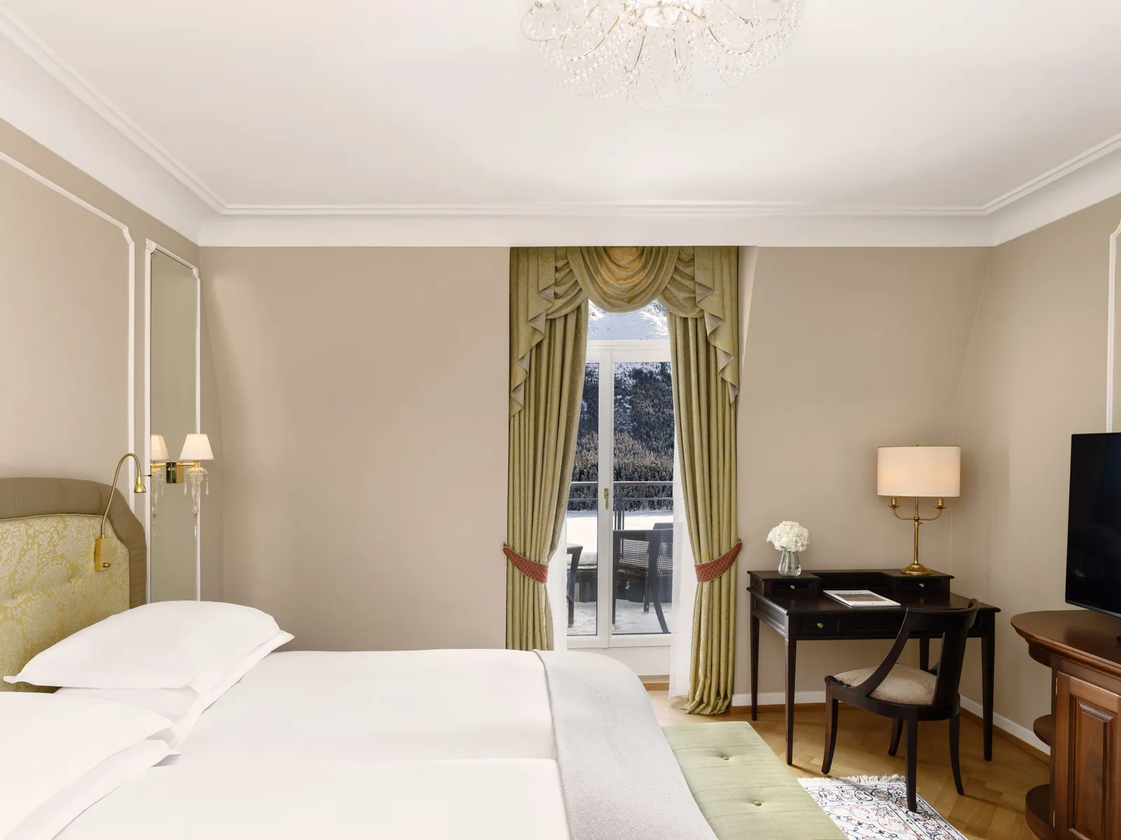 A Deluxe Double Room Lake View: the bed, the dark wood desk and the French window with green curtains and the balcony.