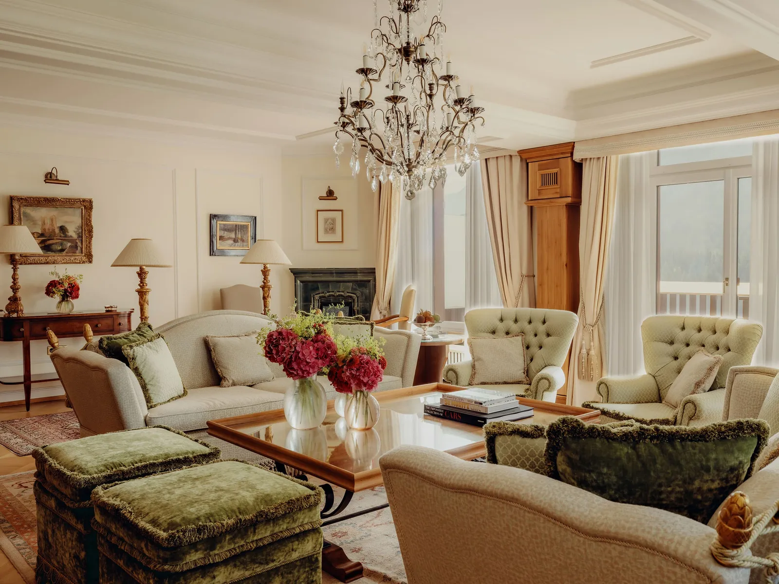 The drawing room of the Helen Badrutt Suite: the iron and crystal chandelier, buttoned sofas, green velvet stools and the fireplace.