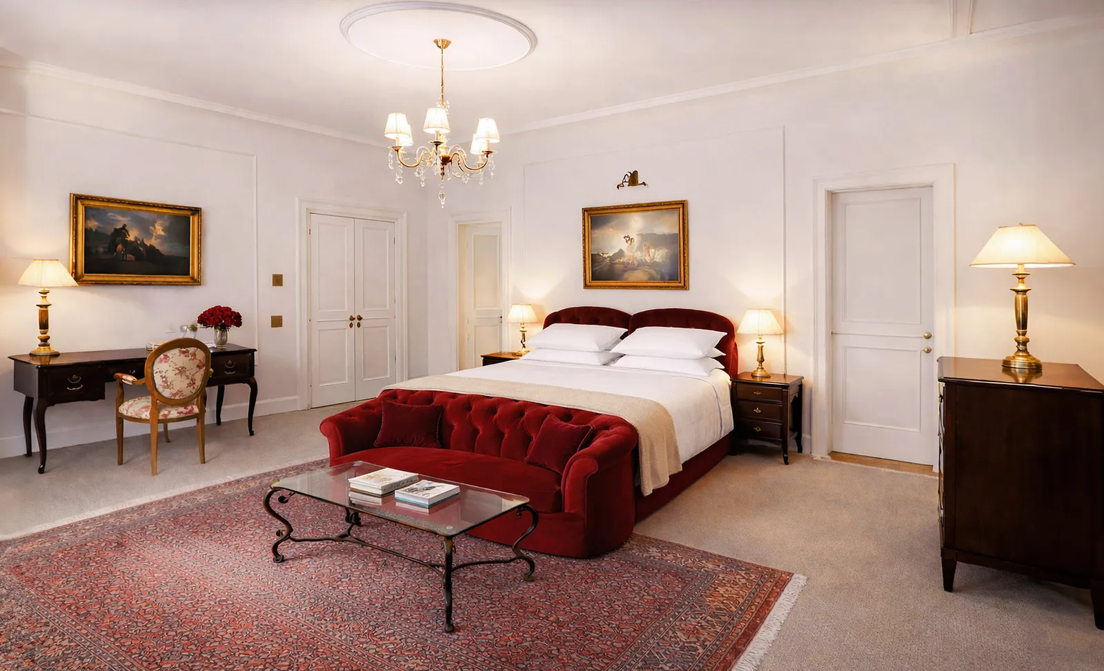A Junior Suite: the bed with a red velvet sofa at its foot, oriental rugs, a writing desk and 2 landscape paintings.
