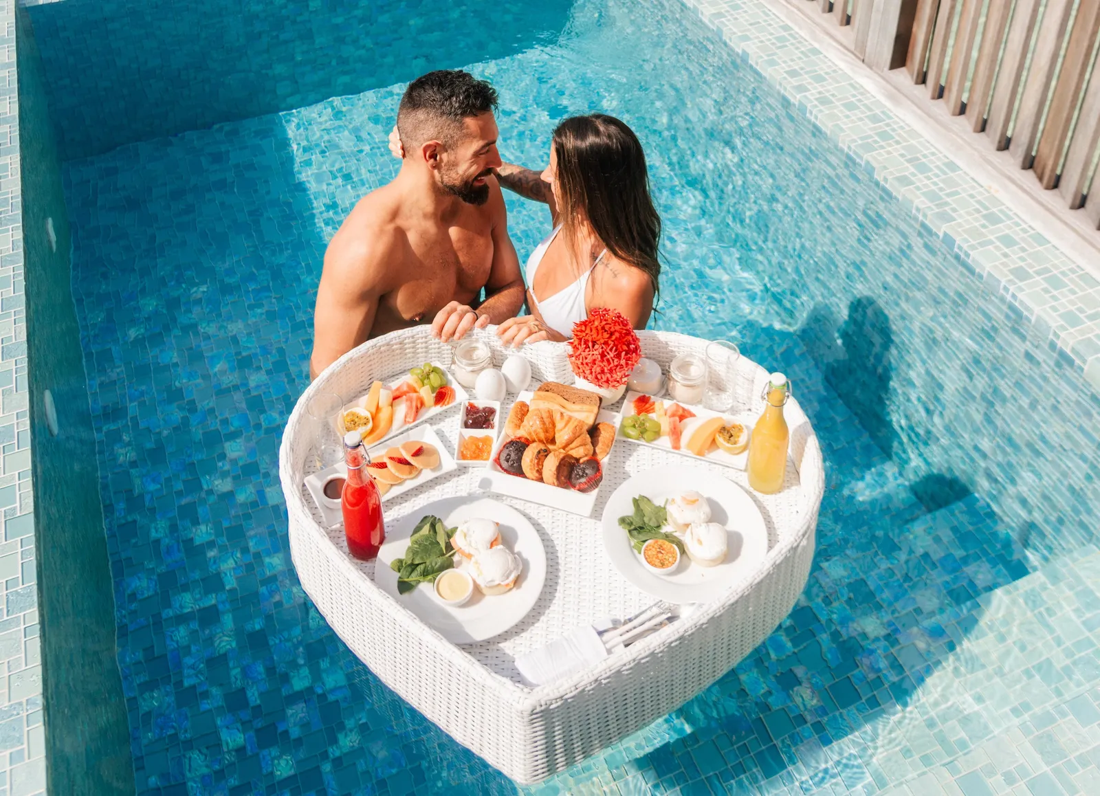 A couple in the villa pool with the floating breakfast tray