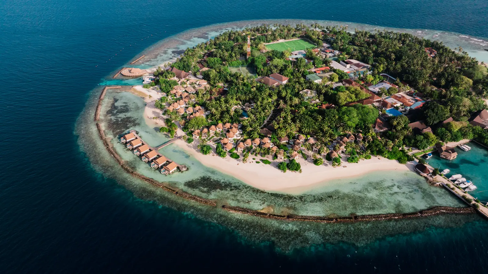 The island from above, the football pitch among the trees, the breakwaters and the jetty