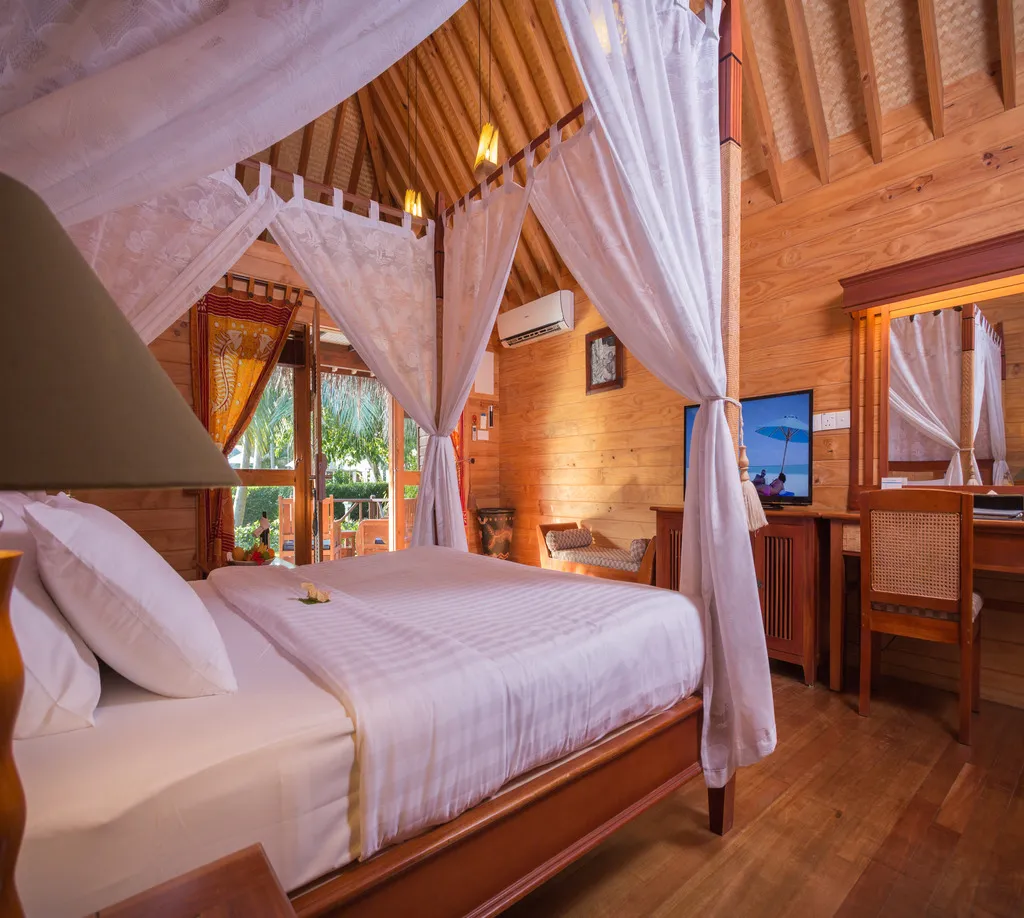A Garden Villa, its four-poster bed between wooden walls