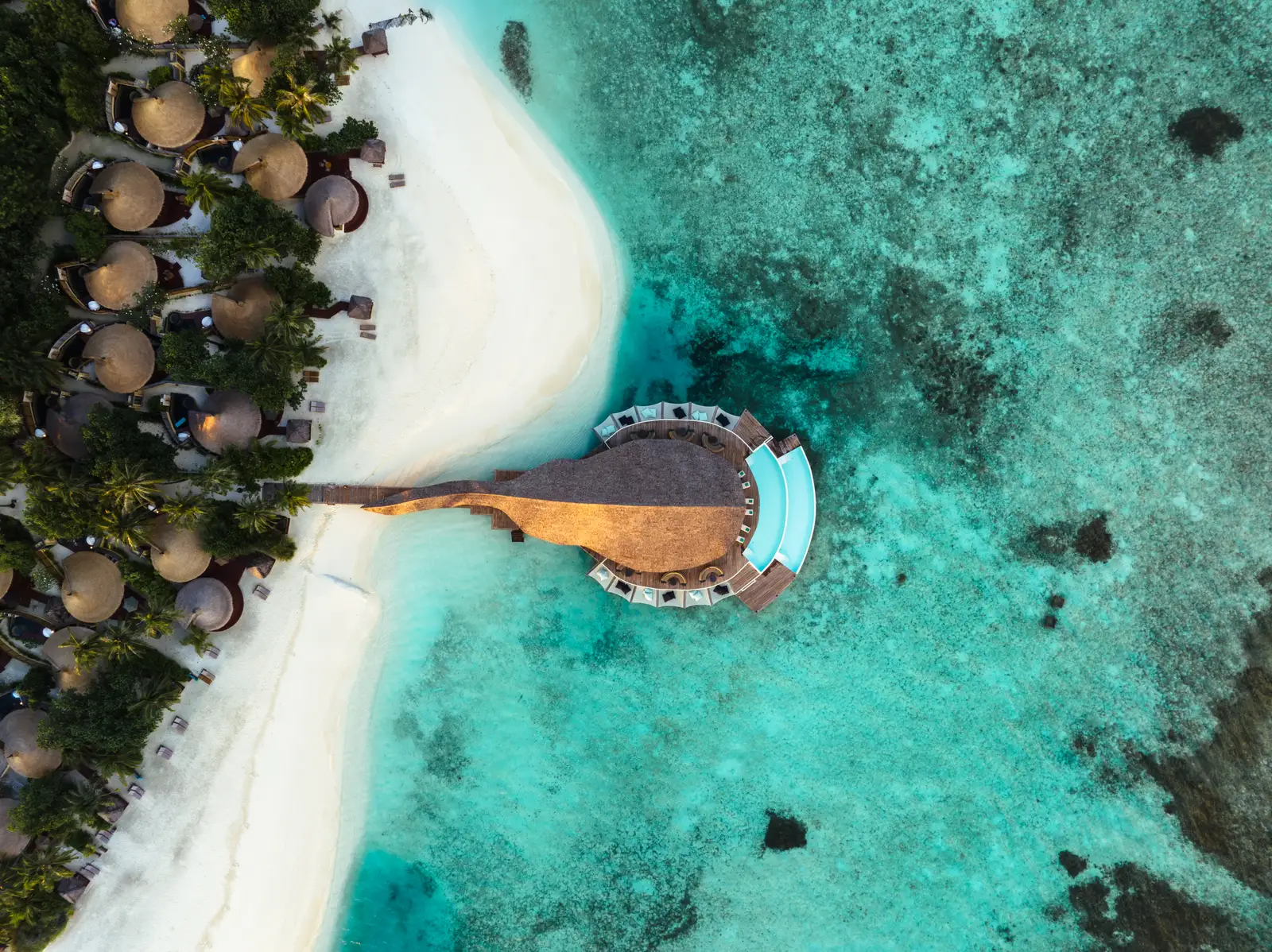 Madi Hiyaa from above: the ray-shaped bamboo restaurant at the end of its jetty, the infinity pool, the beach and the villa roofs among the trees.