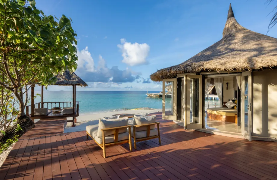 The Grand Beachfront Pool Villa: the thatched villa with its glass doors open, the deck with loungers and the sala on the beach.