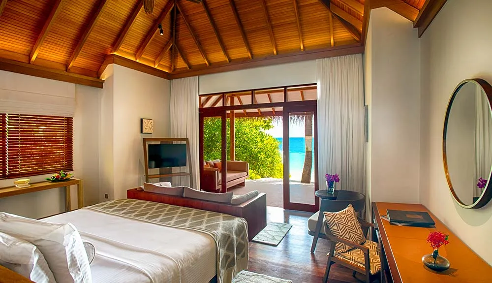 A Deluxe Villa bedroom, its bed and doors open to the garden
