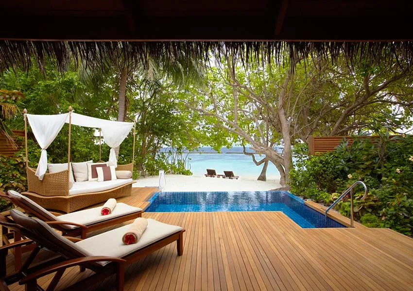 A Baros Pool Villa deck with its canopied daybed, the pool and the beach