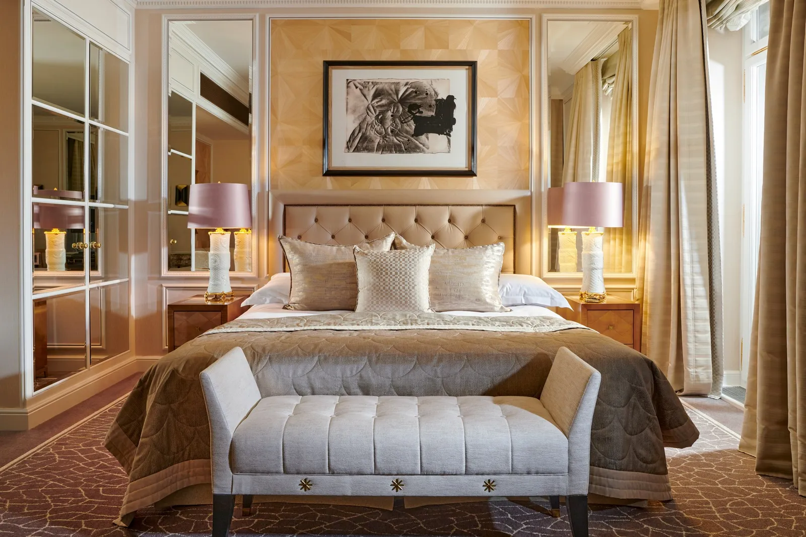 A Double Room: a bed with a padded headboard and a velvet bench at its foot, pink-shaded lamps and mirrored panels
