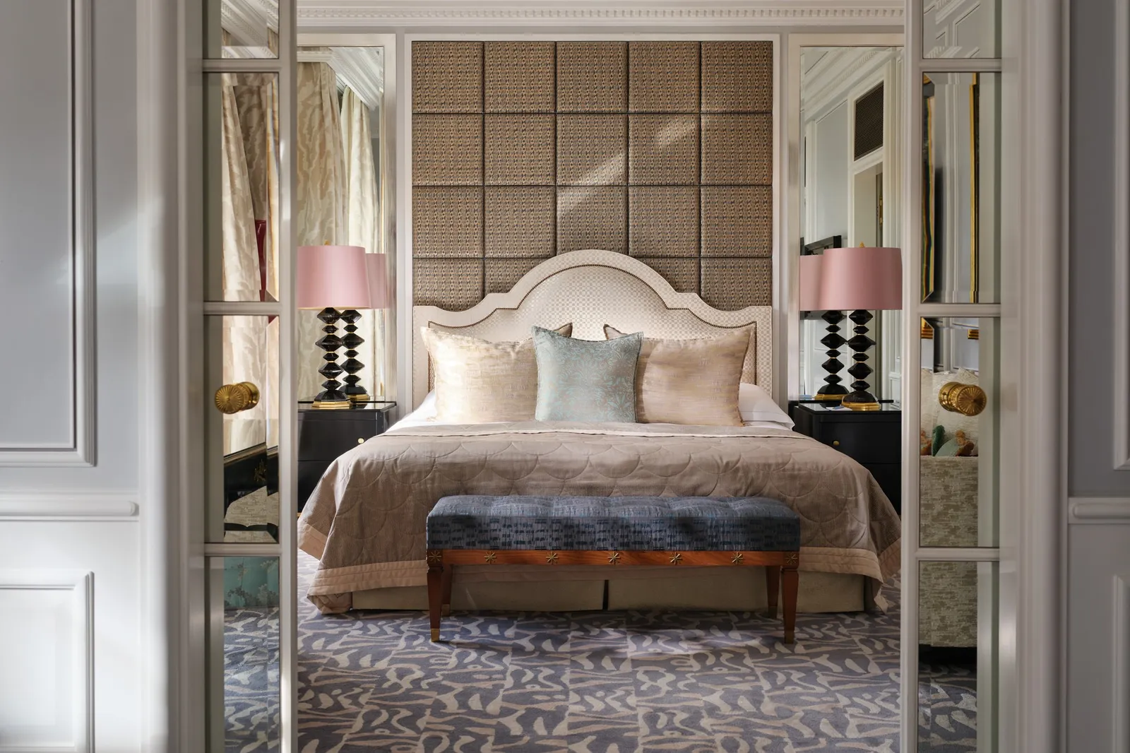 The bedroom of a Lakeside Suite, seen through a doorway: a padded wall, a bed with pale cushions and a navy bench