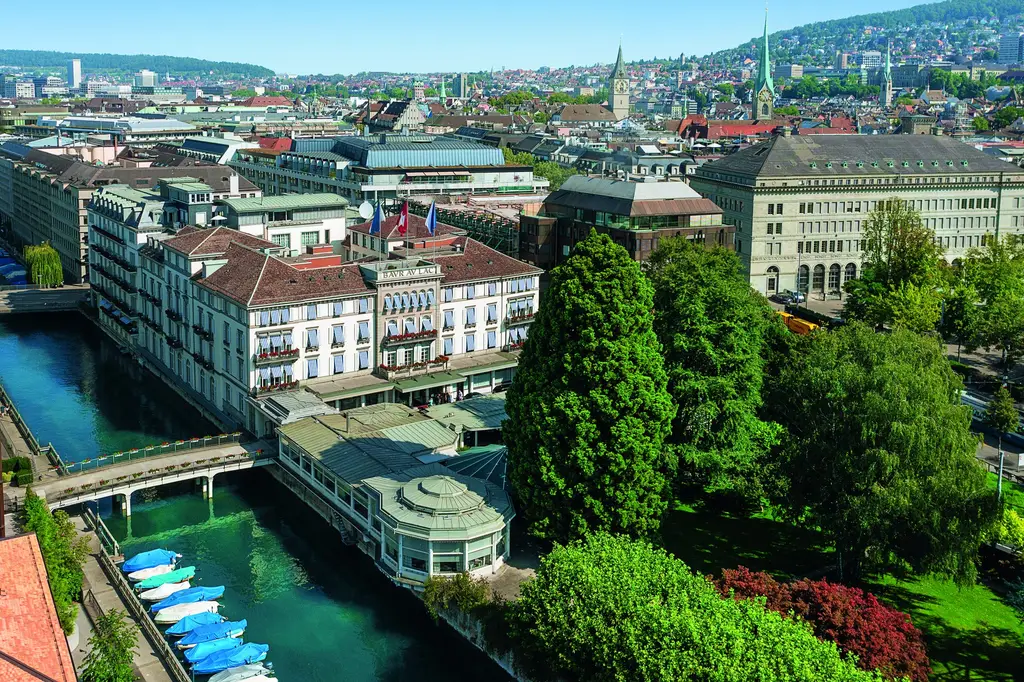 The hotel from above in summer: its park of old trees beside the Schanzengraben, and the roofs and towers of Zurich behind