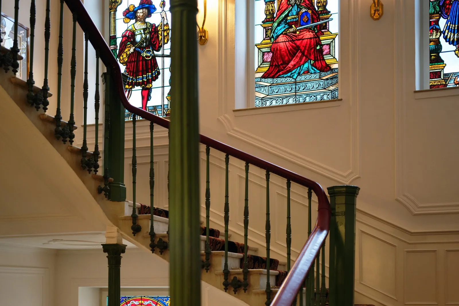 The main staircase with its stained-glass windows by Friedrich Berbig, a wrought-iron banister and a red stair runner