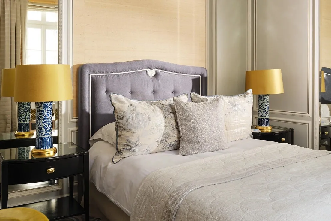 A Single Room: a queen bed with a padded headboard, cushions, 2 lamps and a writing desk