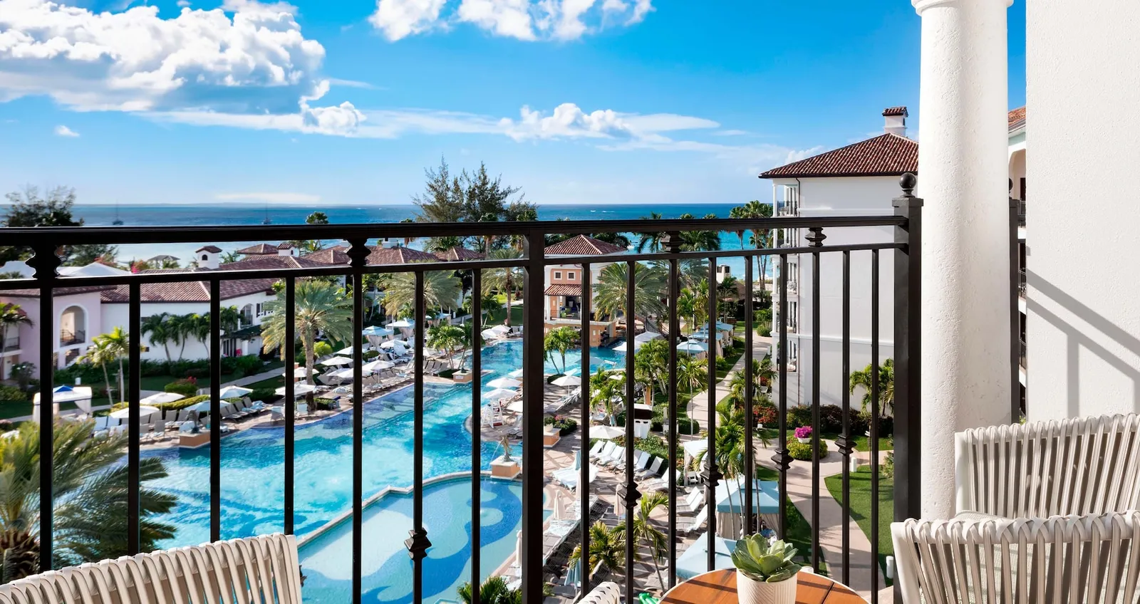From the balcony, the Italian Village pool among palms, the terracotta-roofed buildings and the sea behind.