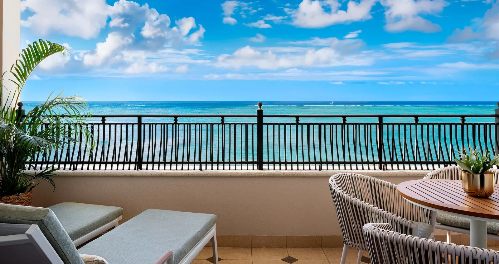 A wide terrace with loungers and a table, a black railing and open sea across the whole view.