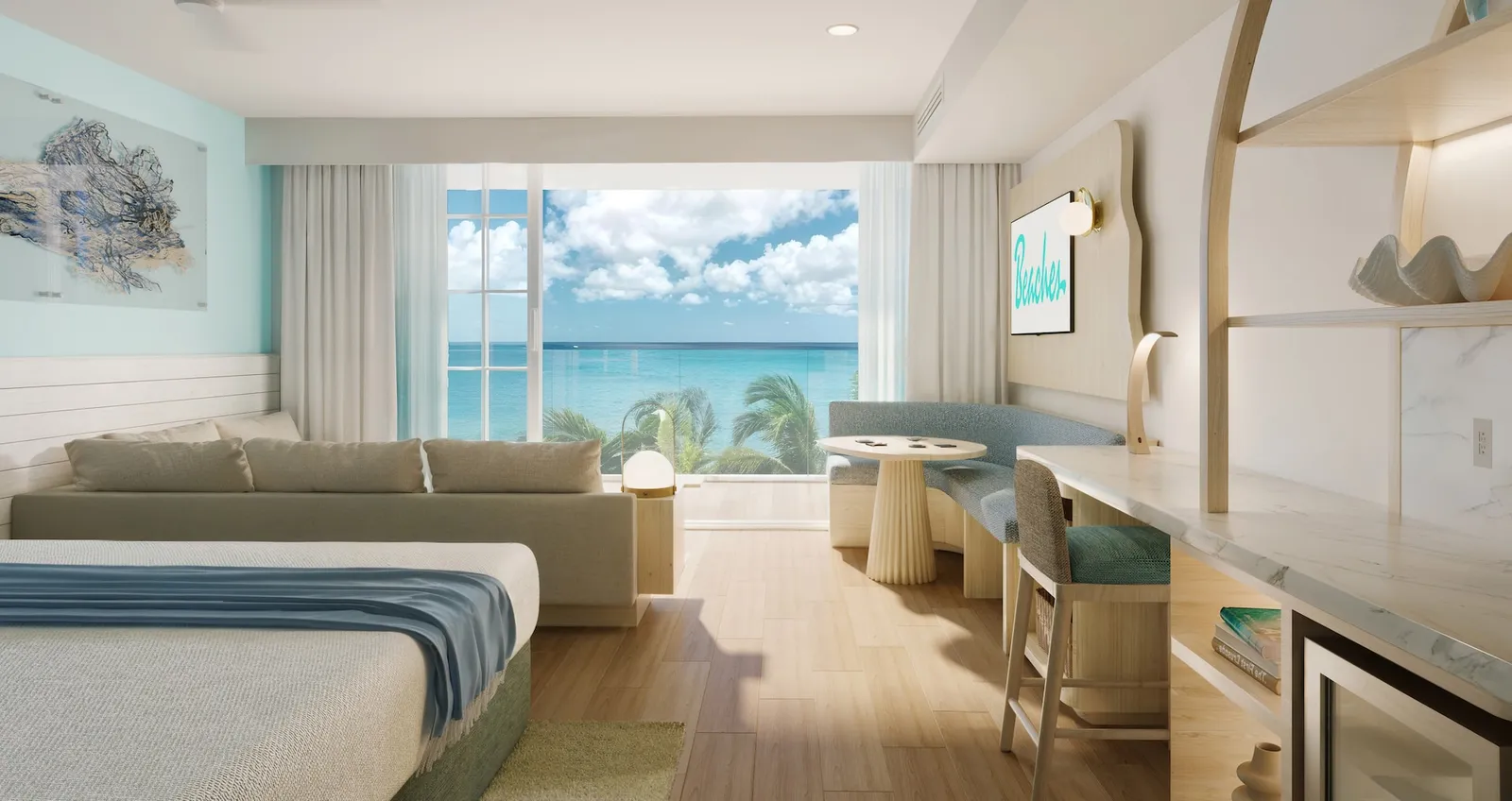 A pale room with a blue throw on the bed, a long sofa, the desk and the window onto the sea and palms.
