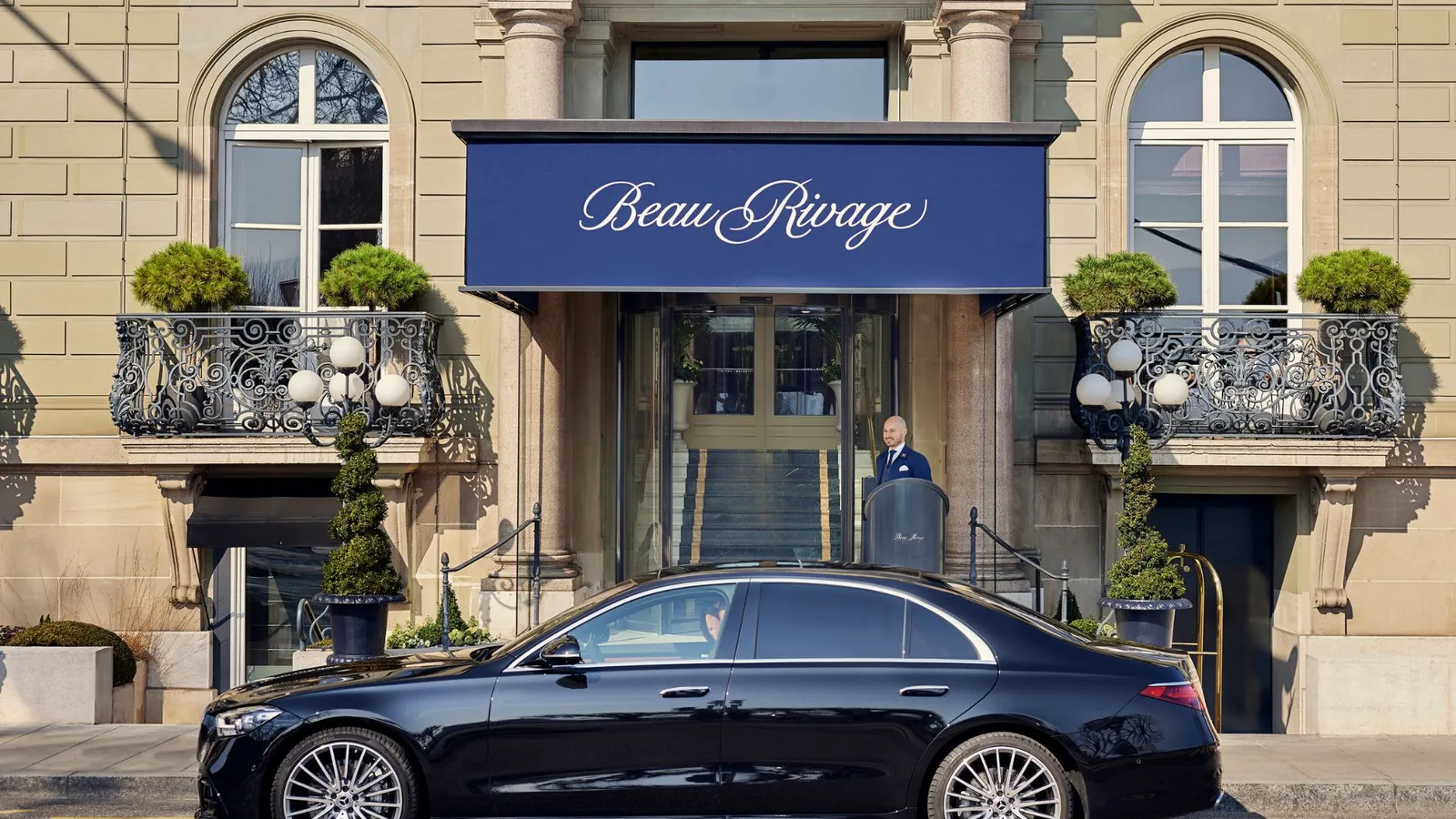 The entrance on the Quai du Mont-Blanc, with its blue awning and a car outside