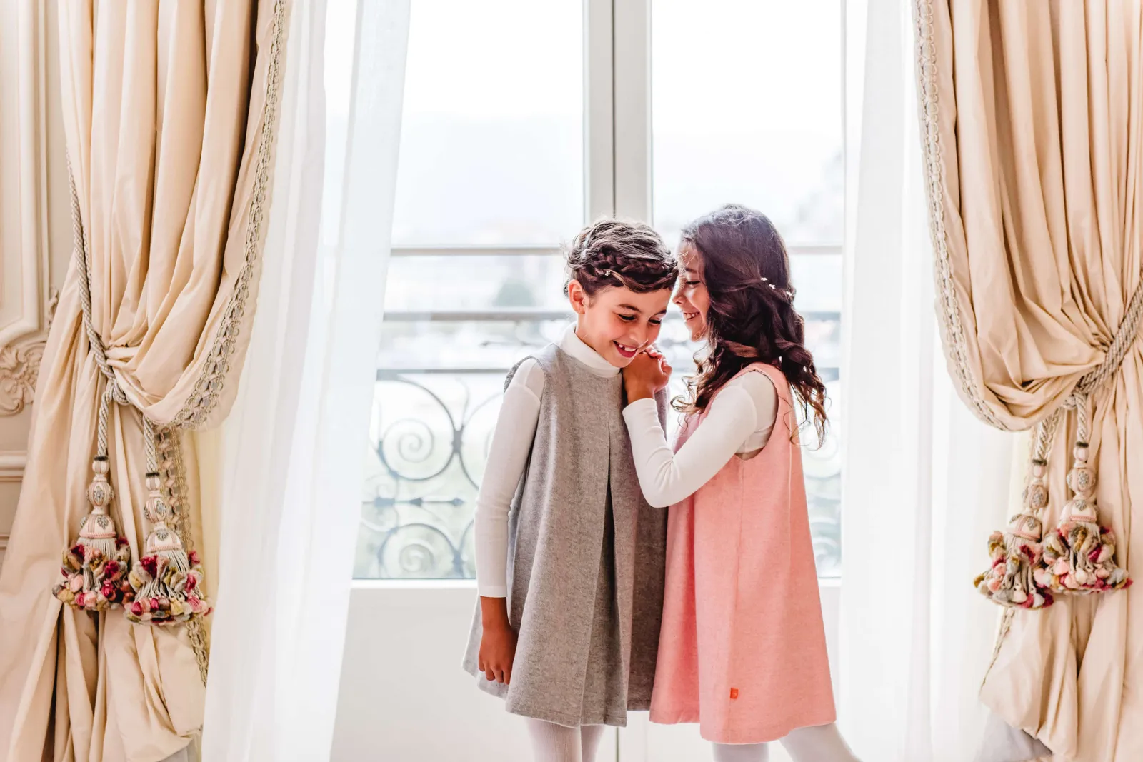 Two children at a suite window, between the curtains