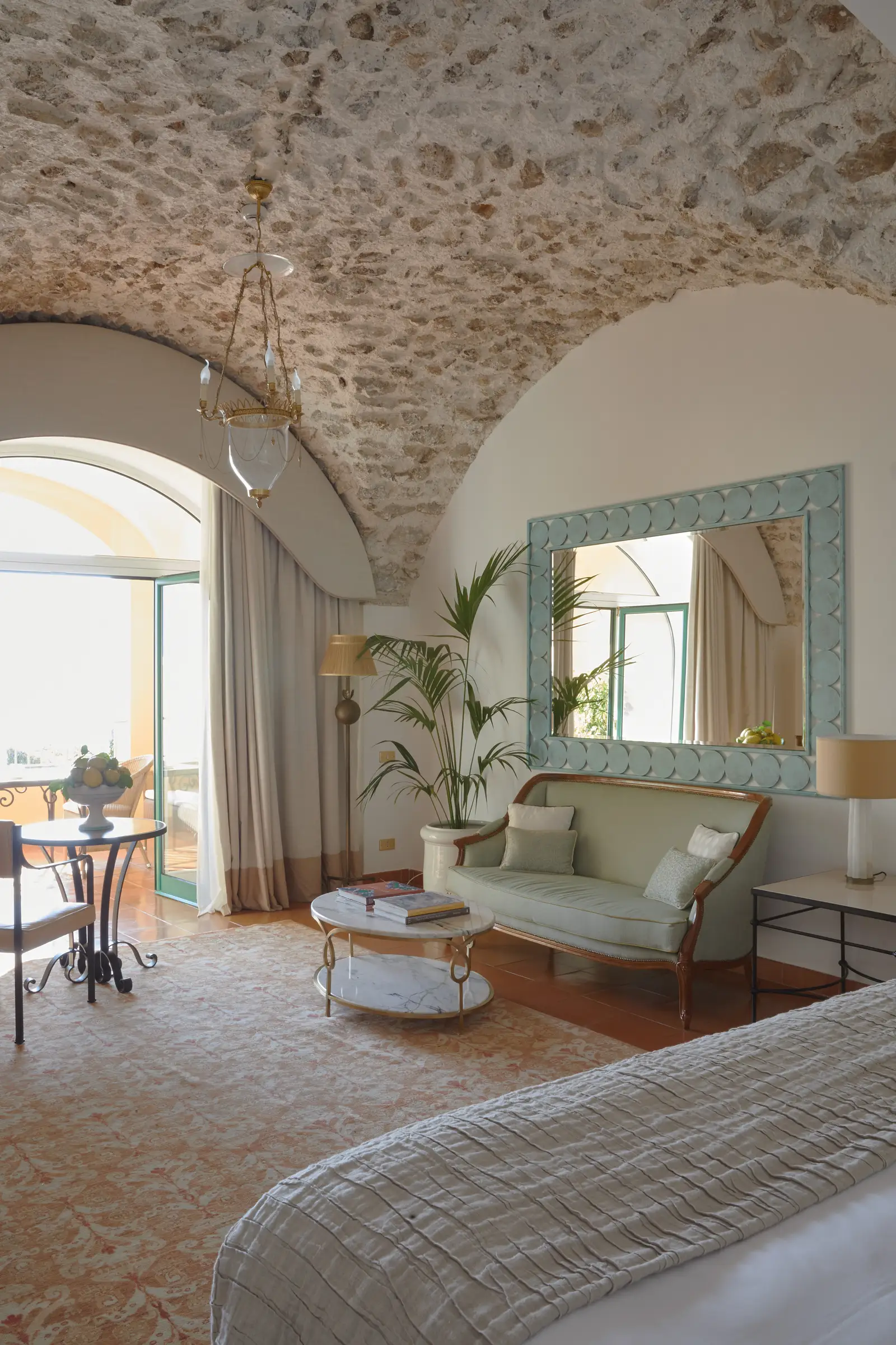 A Superior Sea View Junior Suite with Garden: the sitting area under the stone vault, with the sofa, low tables and the French window open to the outside.