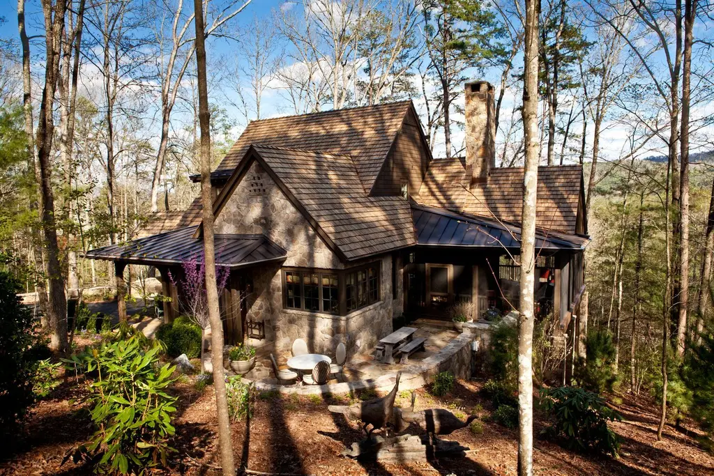 Elkmont in the woods: the house of stone and shingle with its chimney, the stone terrace and tall trees all round.