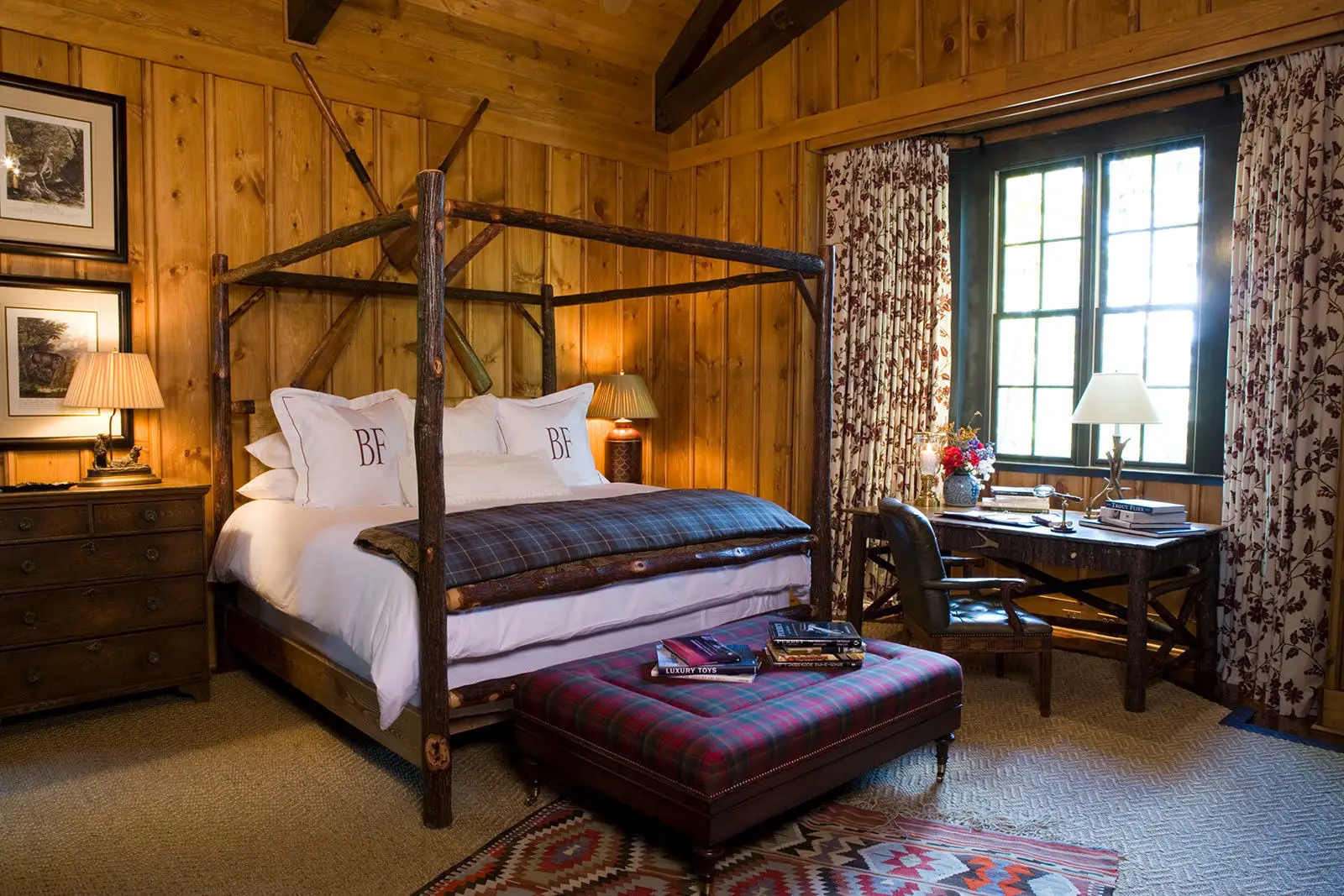 A Hill Cottage bedroom: pine-panelled walls, a twig four-poster, a tartan ottoman and the desk under the window.