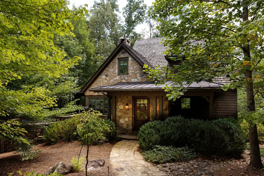 The Roost, a house of stone and timber with a steep roof, at the end of a flagstone path among the trees.