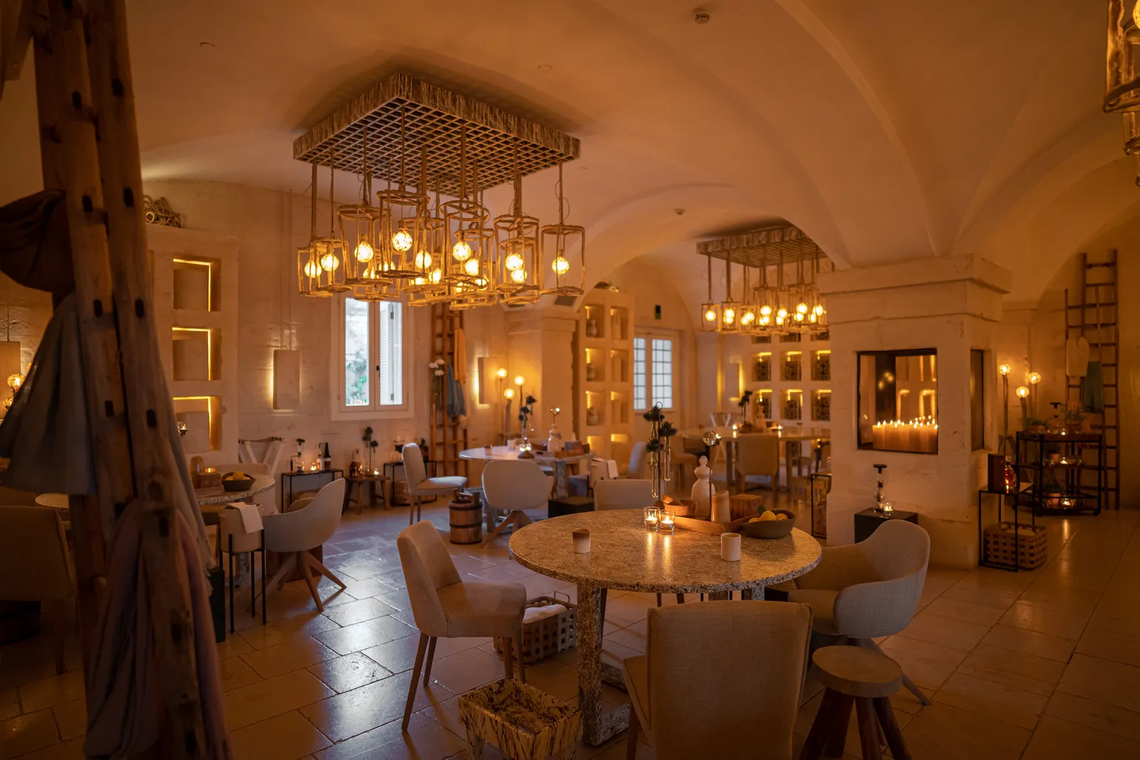 La sala di Due Camini: tavoli rotondi con candele sotto le volte e un camino illuminato da candele.