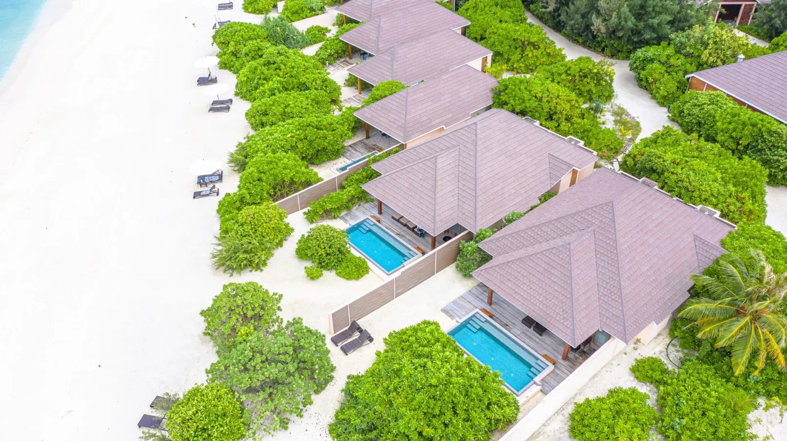 Beach villas with pools, seen from above.