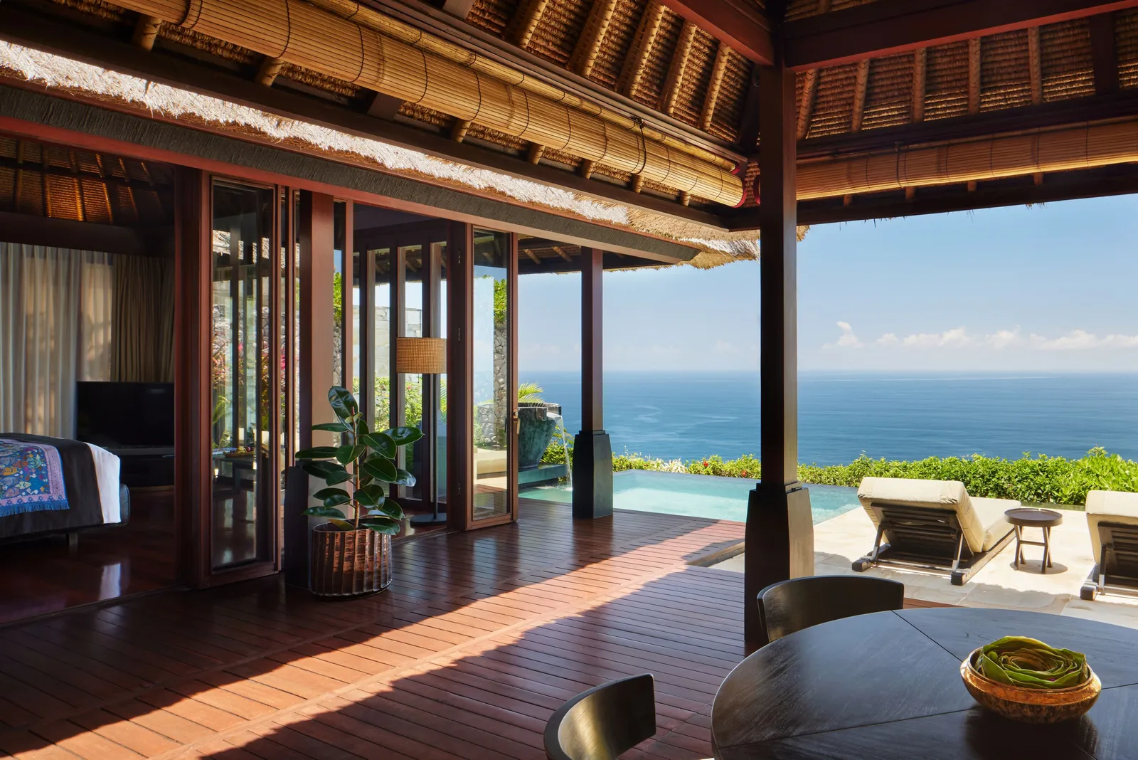 A one-bedroom Ocean Cliff Villa: the wooden veranda, the infinity pool and the open sea beyond the loungers.