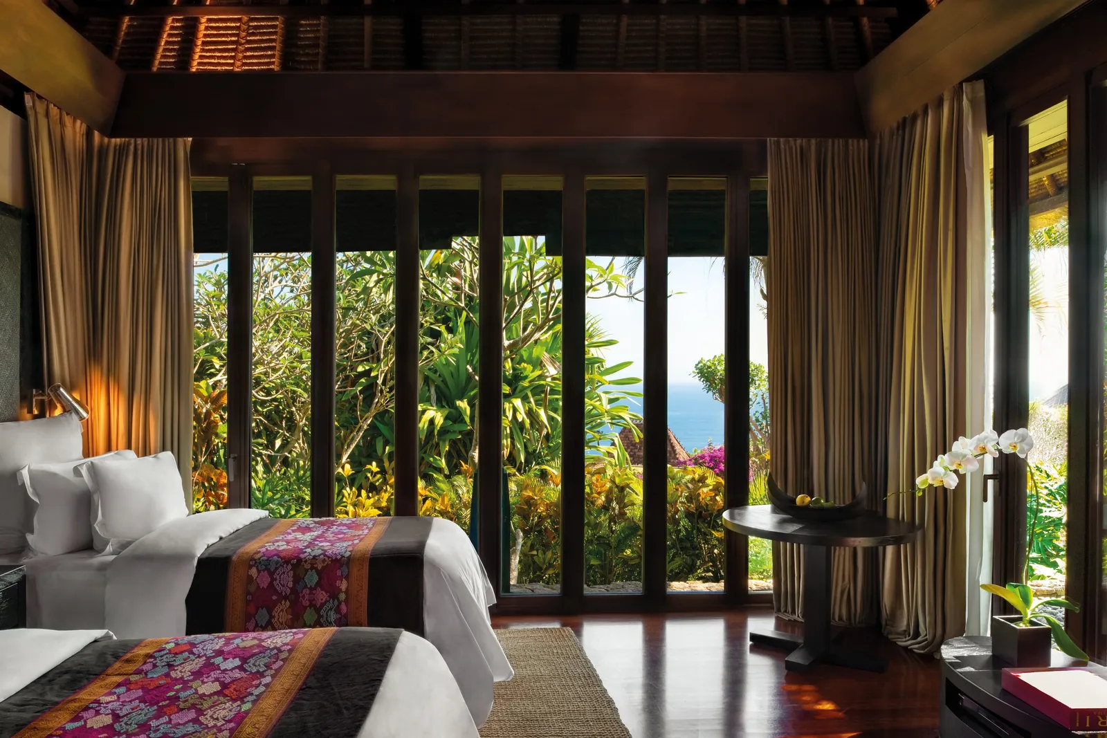 A villa with 2 beds: the hand-woven covers, the curtains and the garden falling away to the sea.