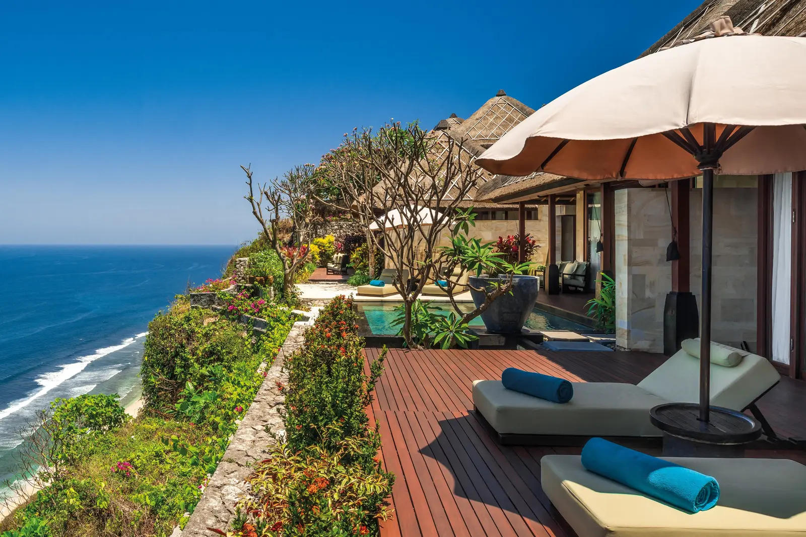 A villa deck on the edge of the cliff, with sunbeds and the ocean below