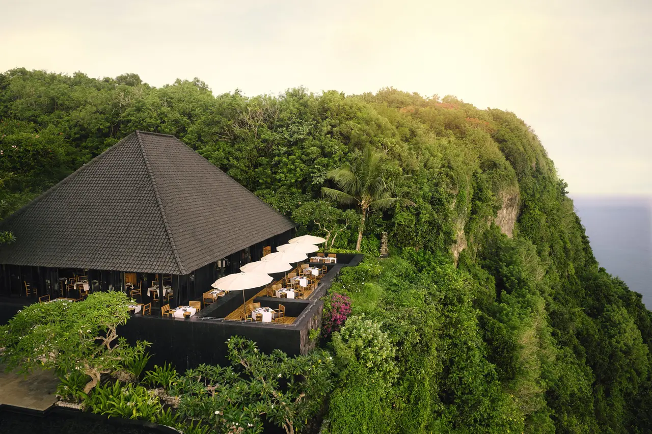 Sangkar from above: the dark pyramid roof and the terrace of white parasols on the highest point of the cliff, thick with green.