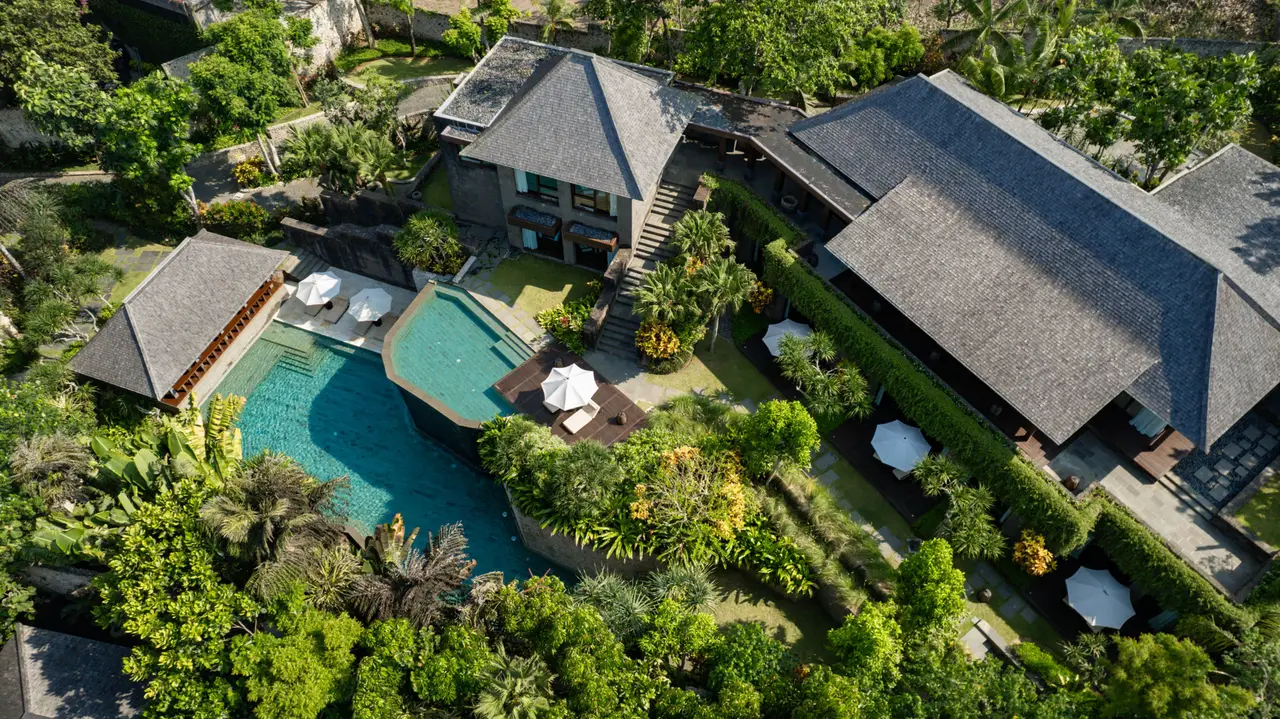 A 5-bedroom Mansion from above: 2 dark-roofed buildings, the 2-tier pools, the parasols and the garden.