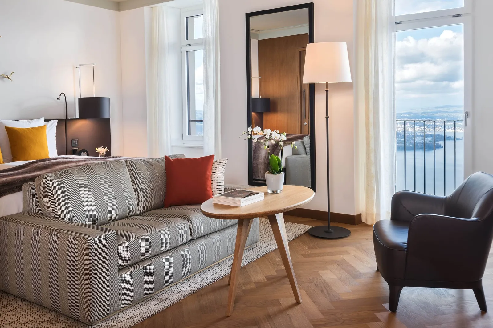 A Heritage Lake View Prestige Room: a sofa at the foot of the bed, a leather armchair and French windows onto a balcony over the lake