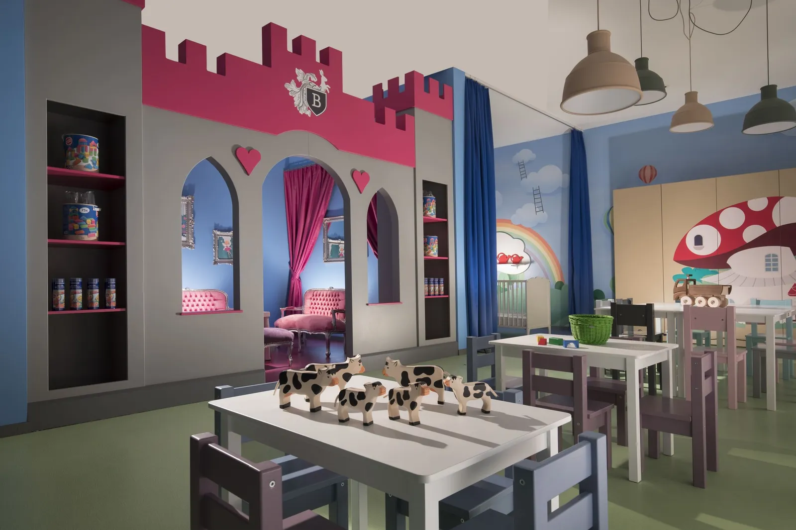 The Kids Club: a play castle with pink battlements, small tables with toy cows, a mushroom house and a painted sky