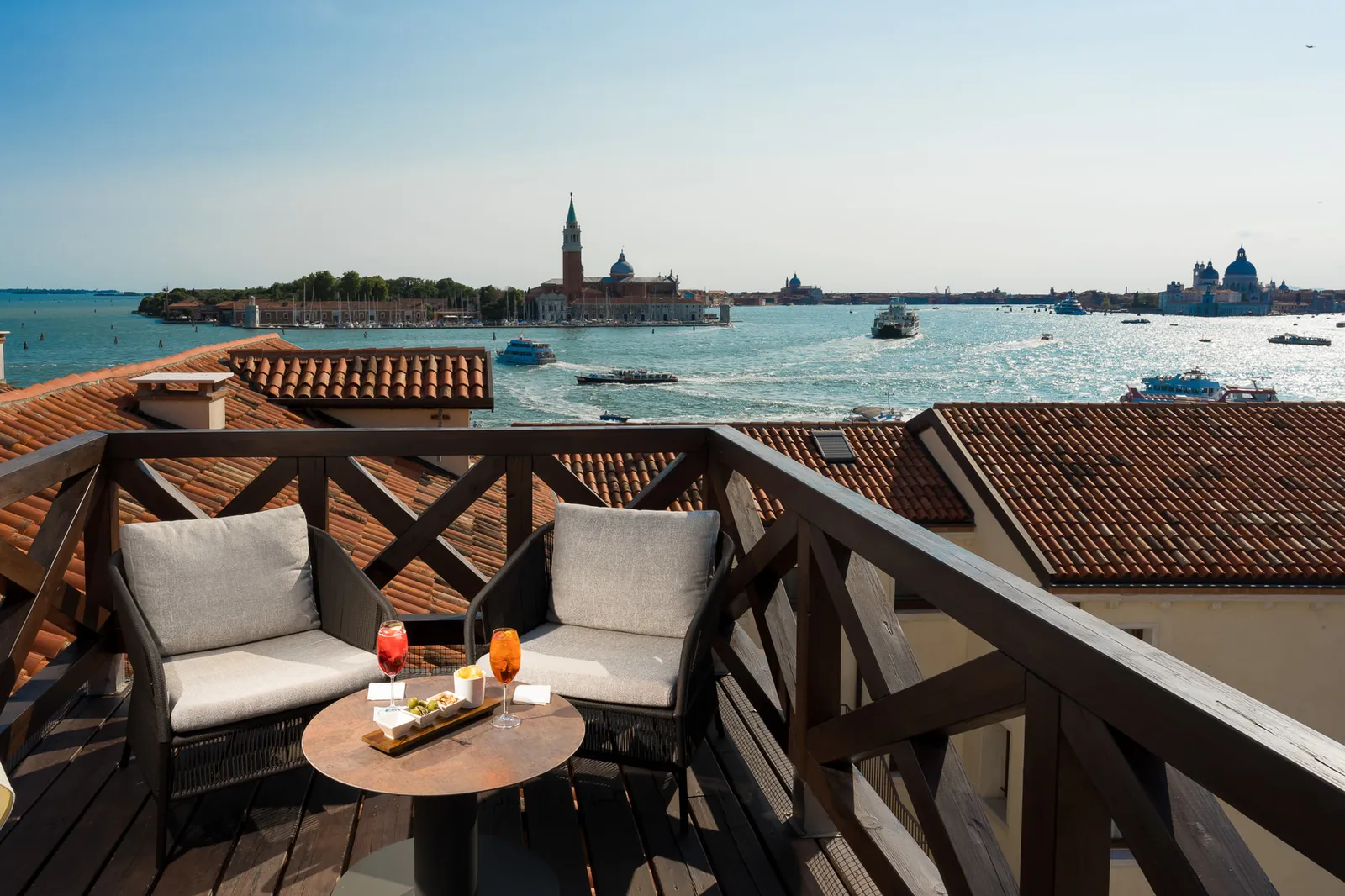The Altana Suite’s rooftop altana: 2 armchairs on the wooden deck above the roofs, the lagoon and San Giorgio