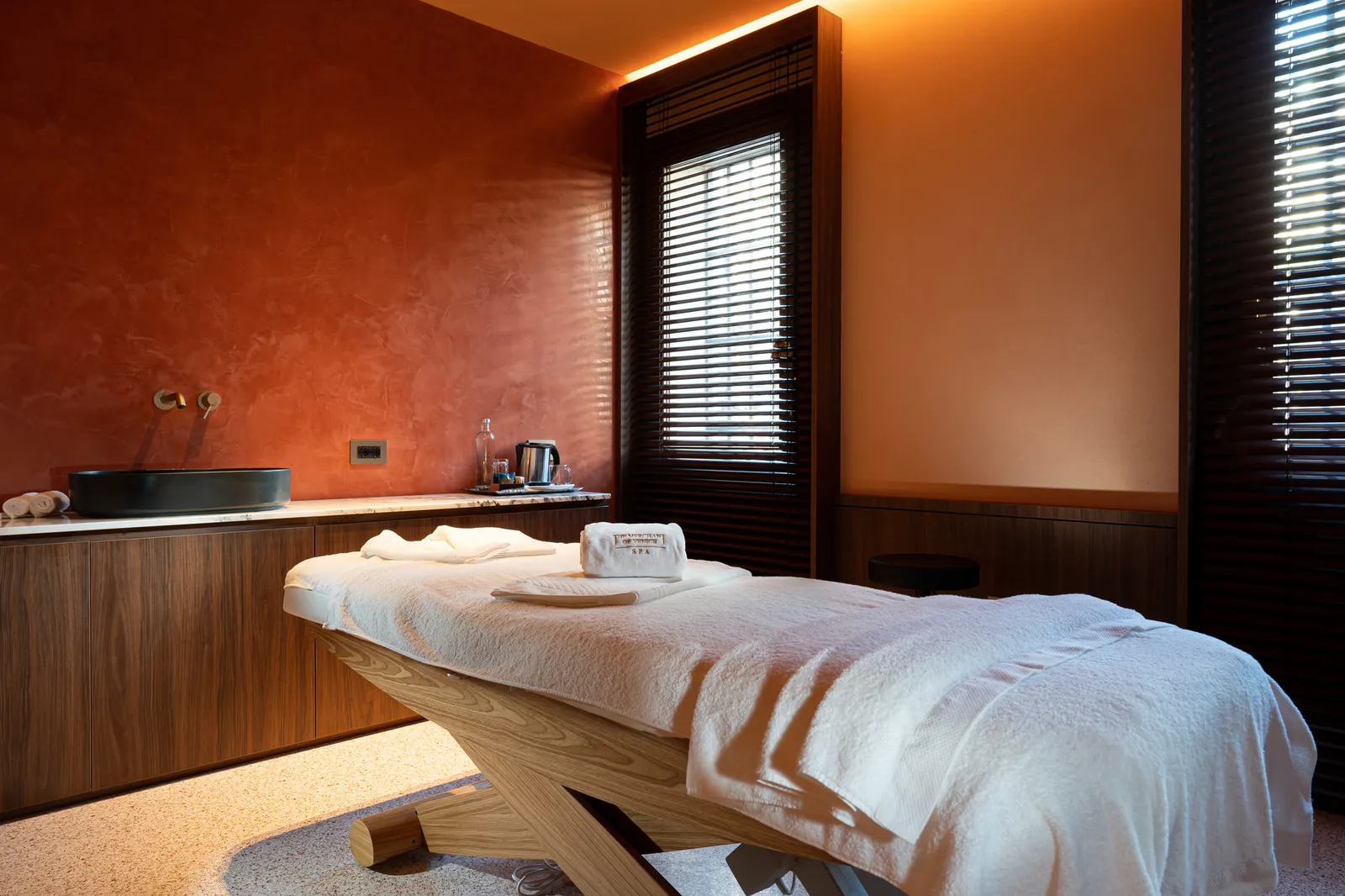A treatment room at the Pura City Spa, with the massage bed and a terracotta wall