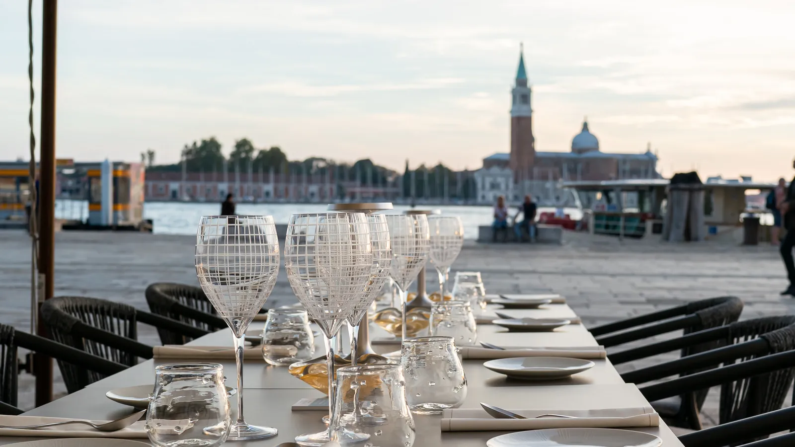 Tables laid on the waterfront in front of the hotel, with San Giorgio Maggiore across the basin at sunset