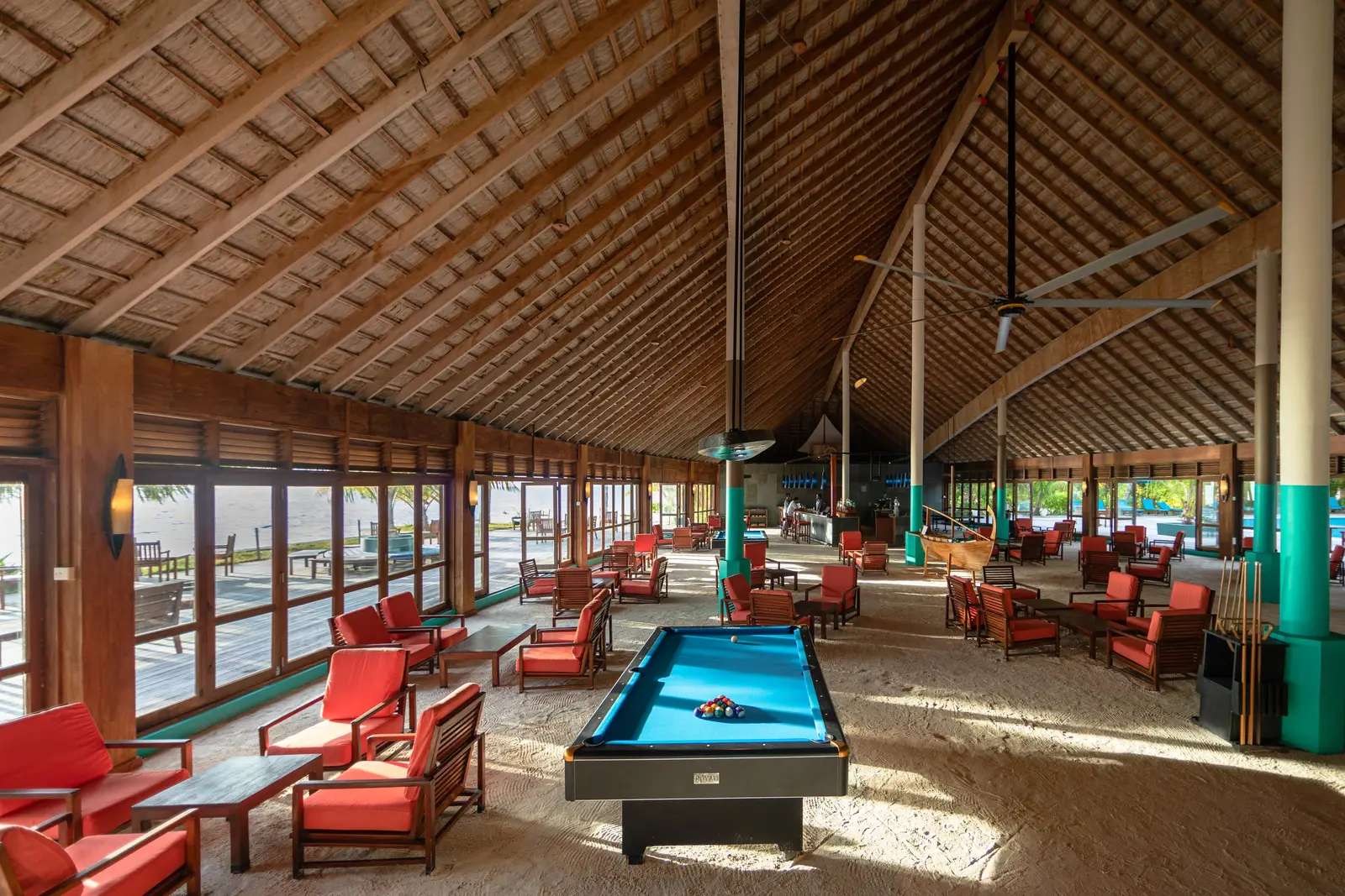 Inside the Dhoni Bar under its thatched roof, the pool table and red armchairs