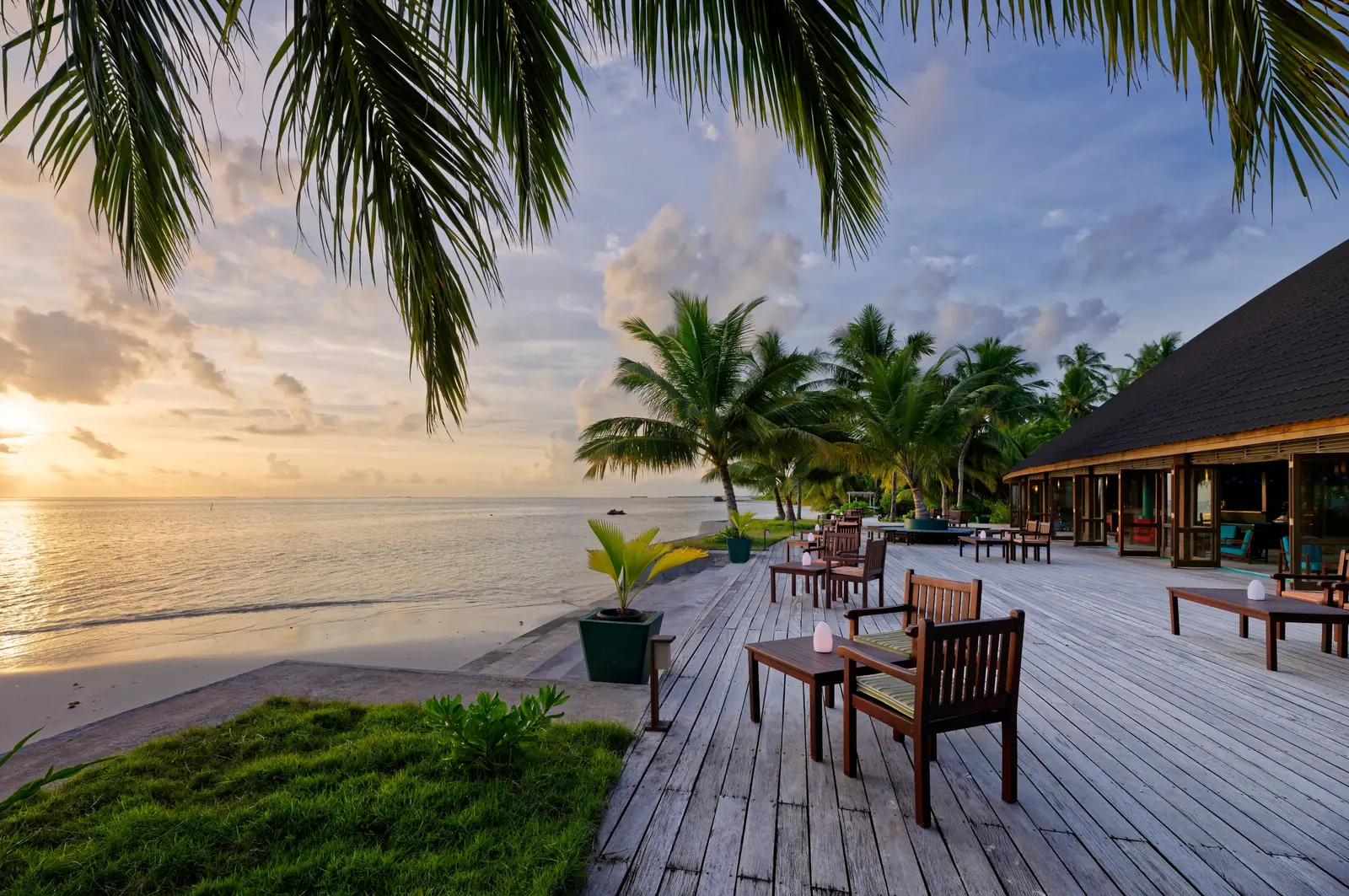 The Dhoni Bar’s deck at sunset, wooden tables facing the sea