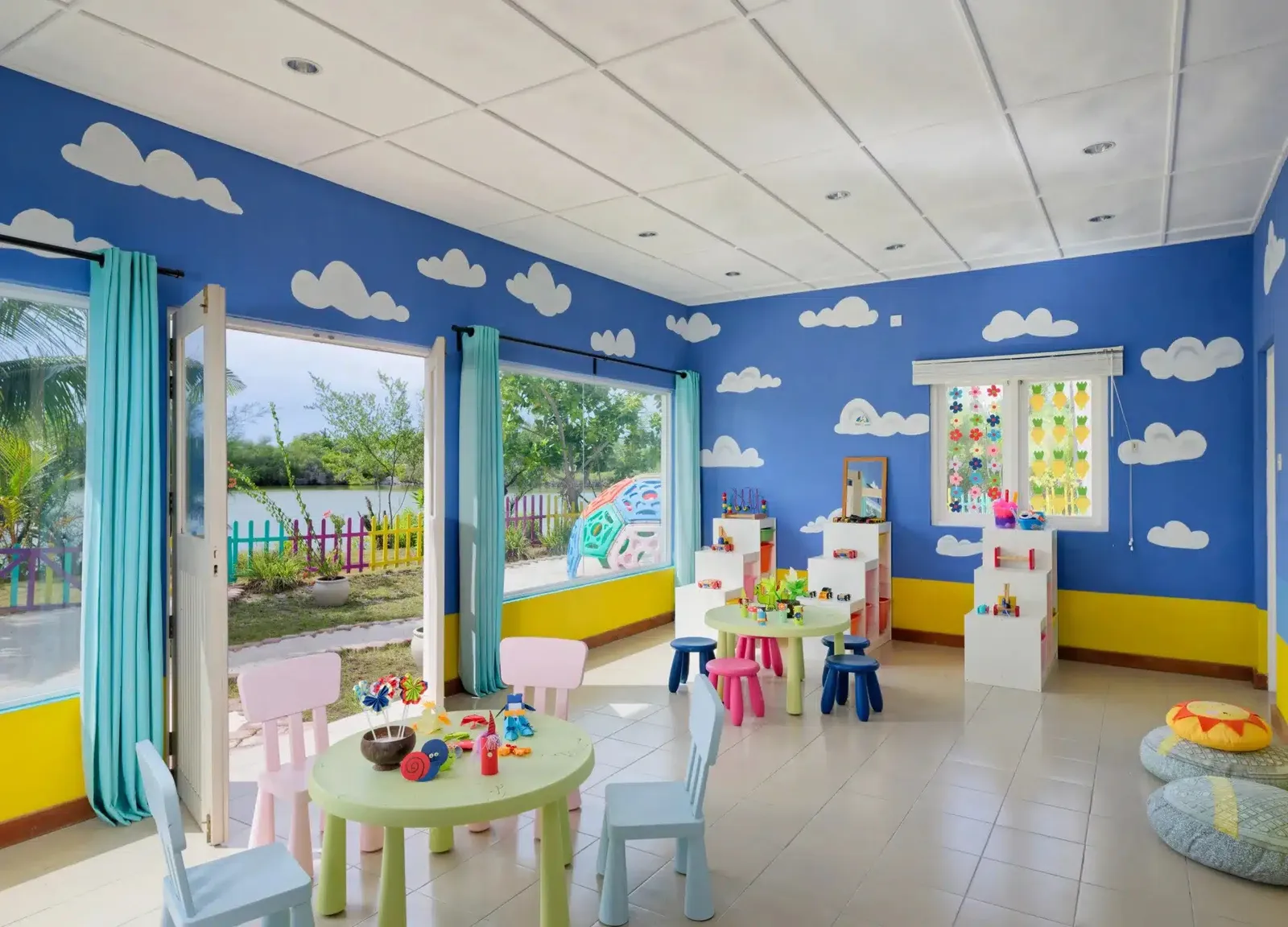 The kids’ club room, blue walls painted with clouds and small bright tables