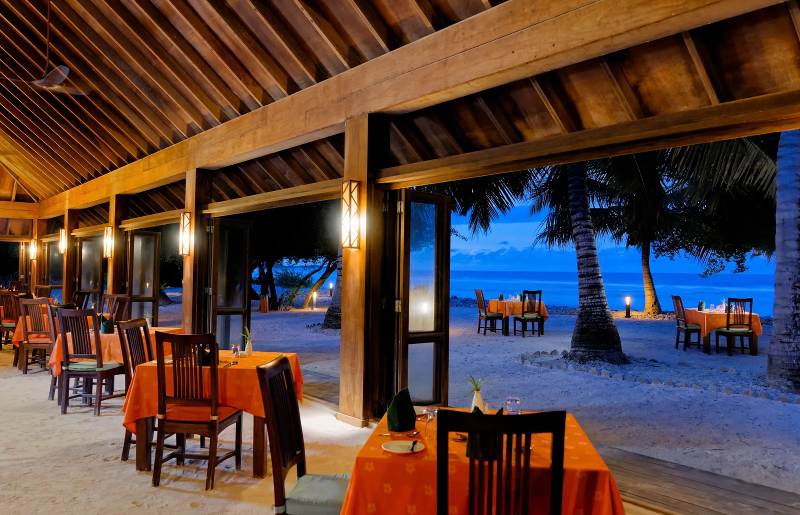 The Kilhi Restaurant in the evening, its laid tables and the beach beyond the pillars