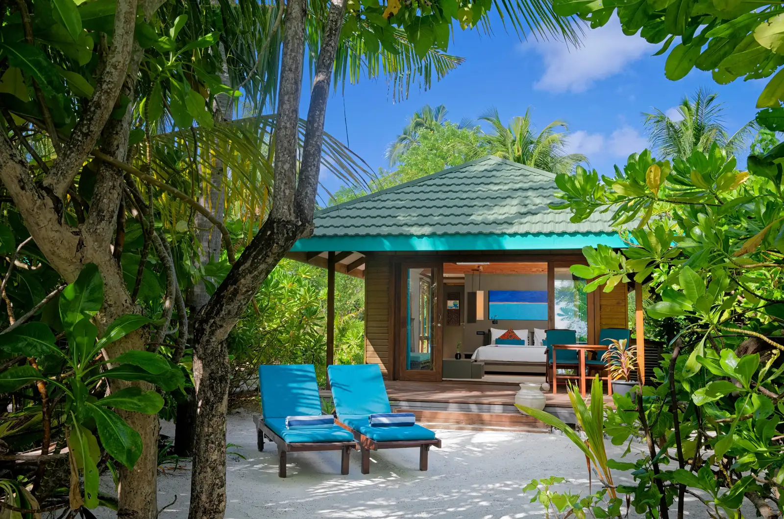 A Sunset Beach Villa among the trees, turquoise loungers on the sand