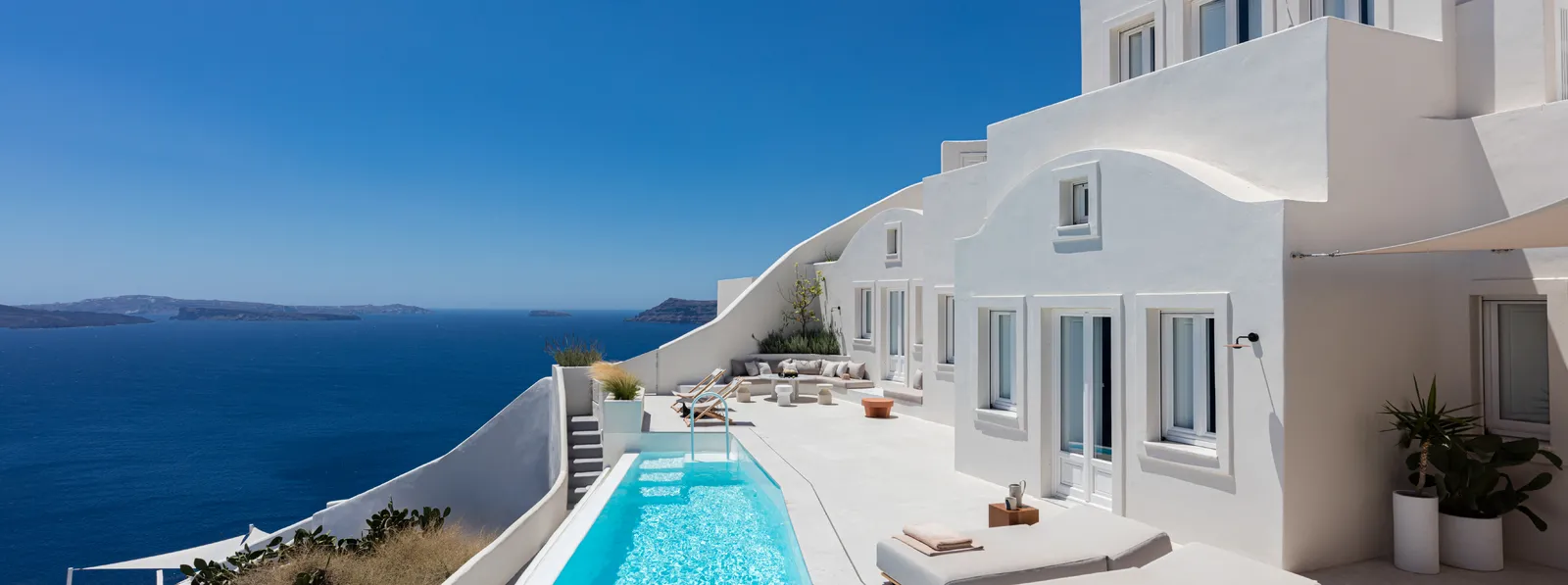 The white suites stepped down the cliff, with a long, narrow pool, loungers on the terrace and the sea of the caldera.