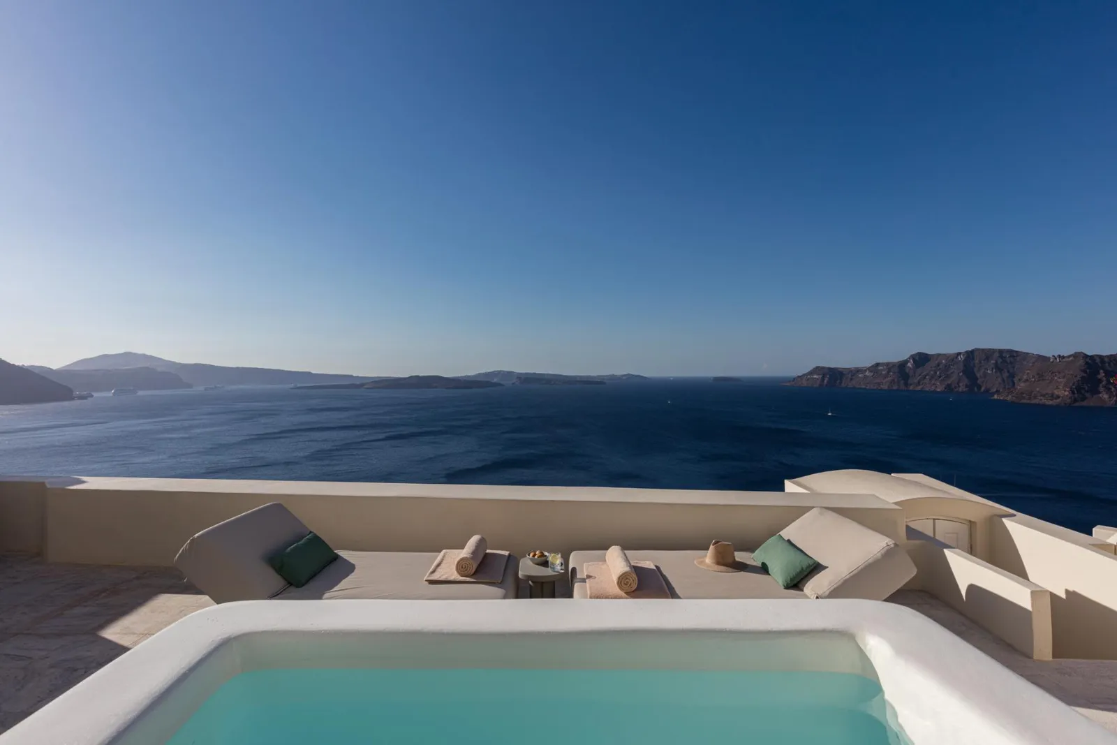 A Honeymoon Suite’s plunge pool, with loungers at its edge and the caldera on the horizon.