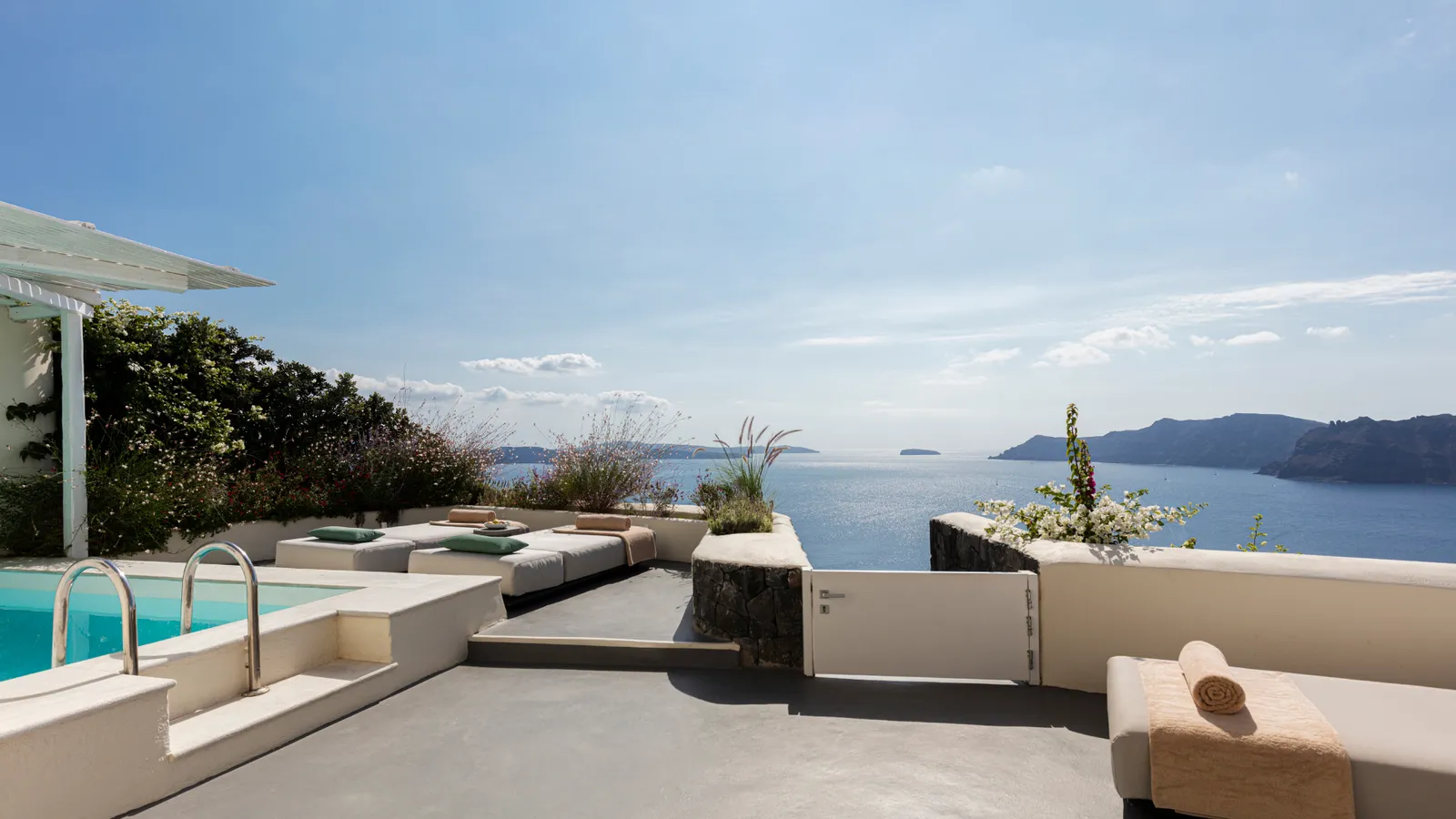 The Canaves Suite’s terrace: the pool with its ladder, the loungers and the caldera under a hazy sky.