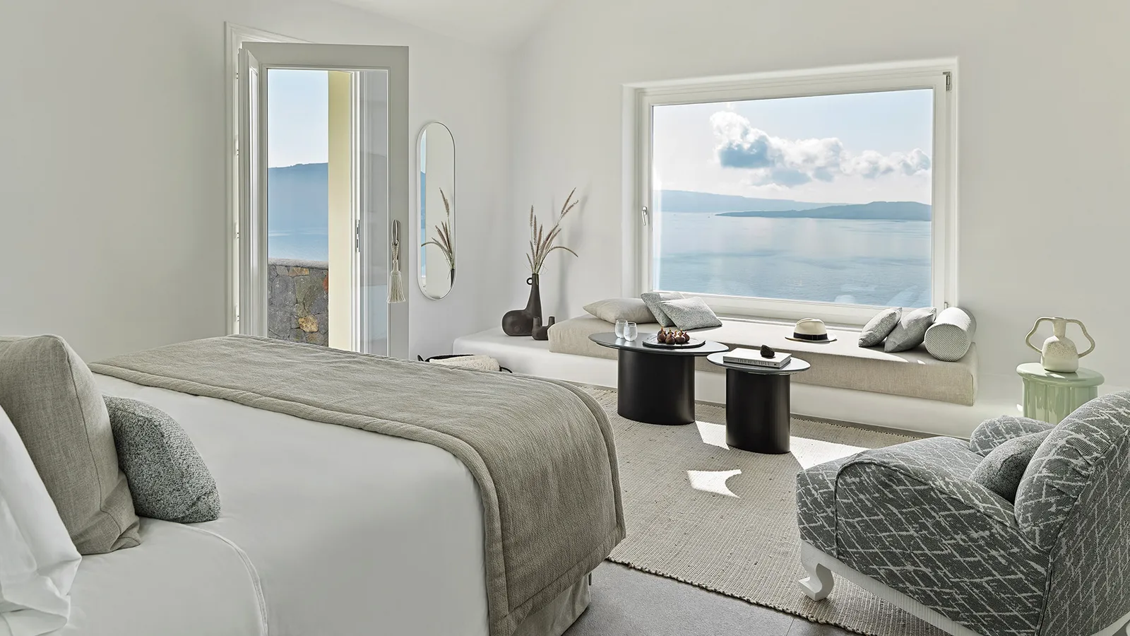 An Executive Pool Suite: the bed, an armchair, black side tables and the large window onto the sea.