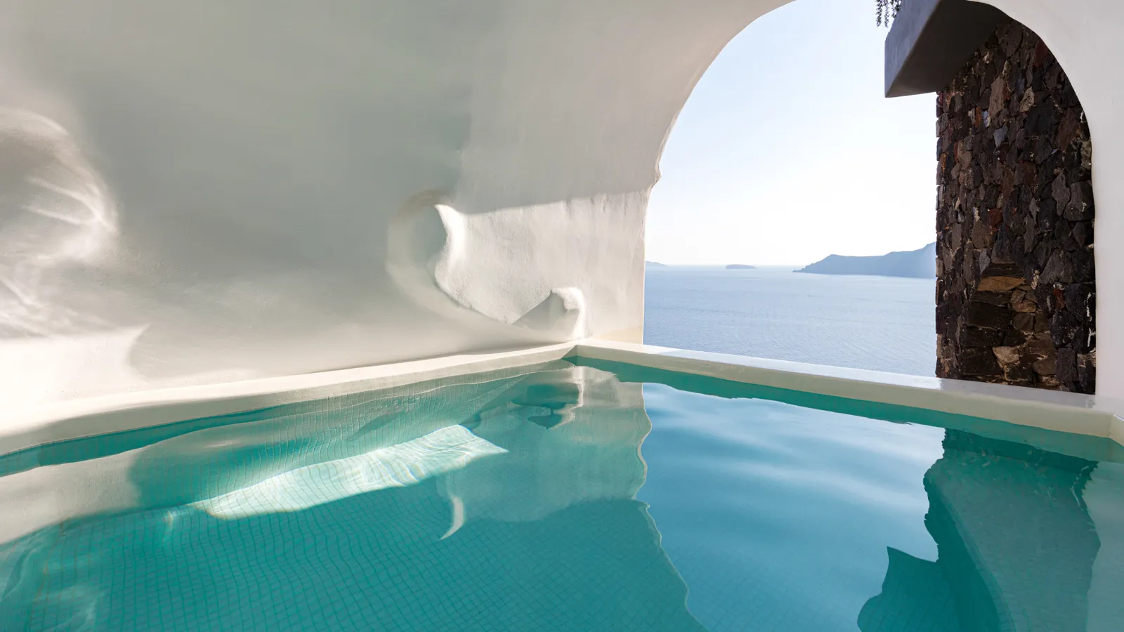 The Executive Suite’s cave pool: green water under a sculpted white vault and a wall of lava stone.