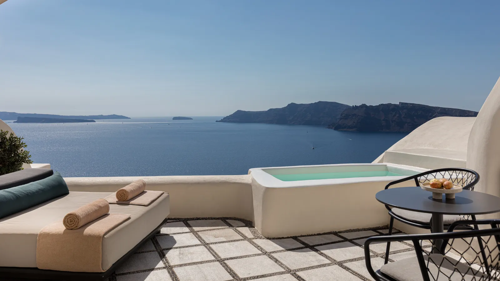 A Honeymoon Suite terrace: a daybed, a round table with 2 chairs, the plunge pool and the sea.