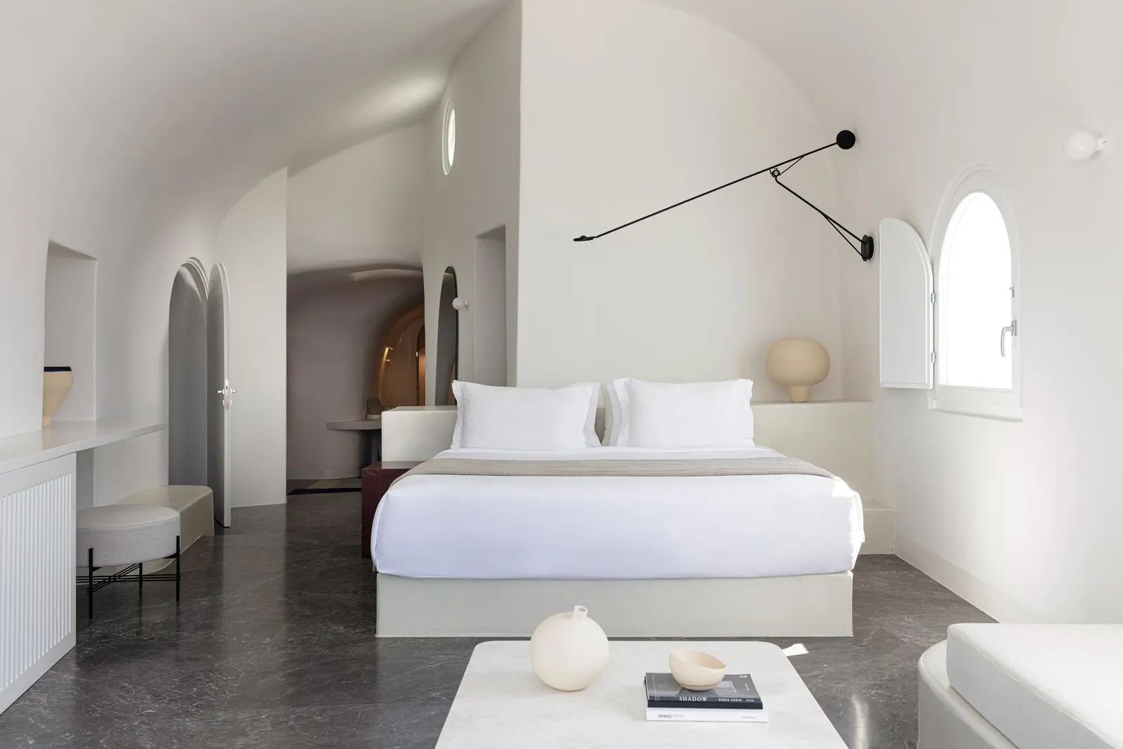 A bedroom of the Two Bedroom Pool Villa: the white bed under the vault, a black swing-arm lamp and an arched window.