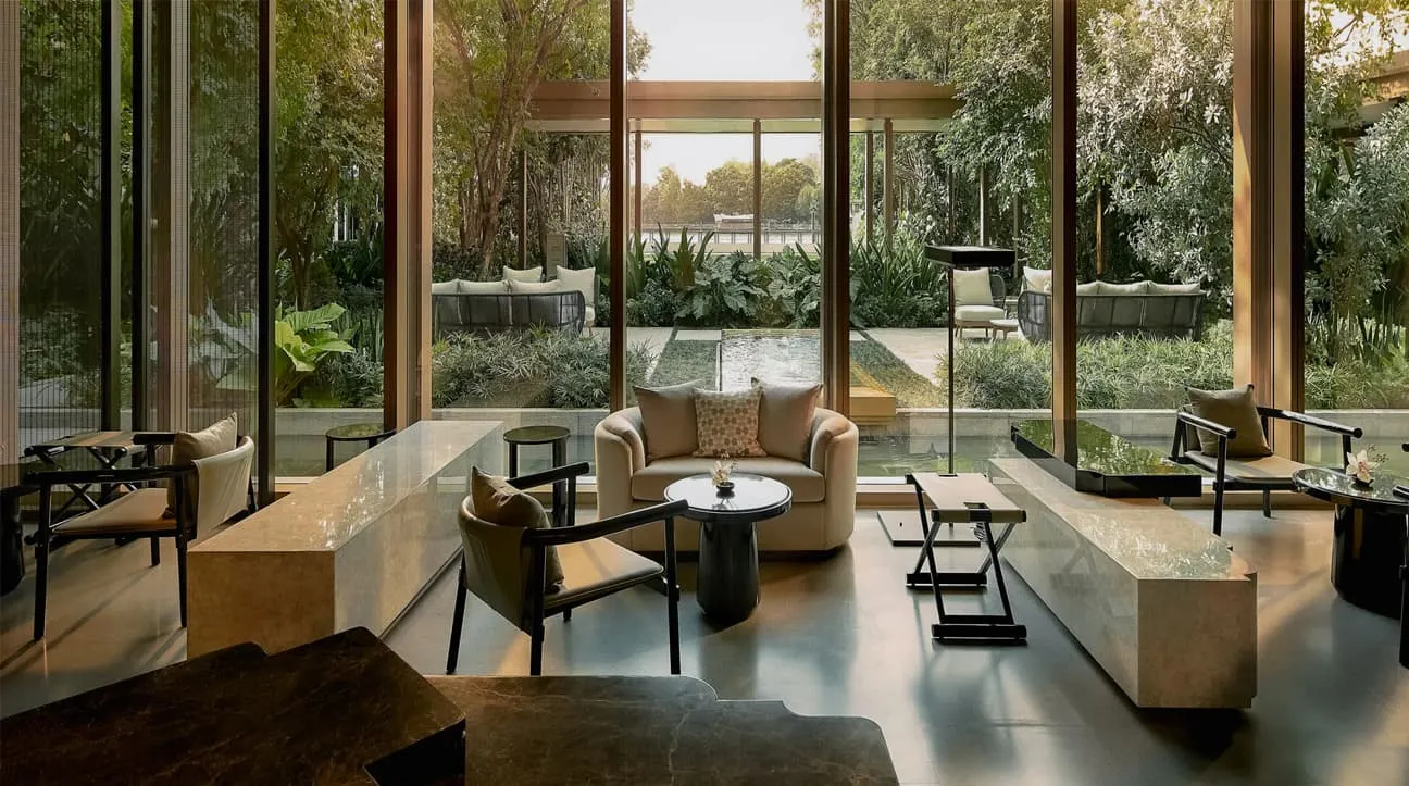 La lounge di Auriga Wellness: poltrone basse e un tavolo di pietra davanti alle vetrate sul giardino.